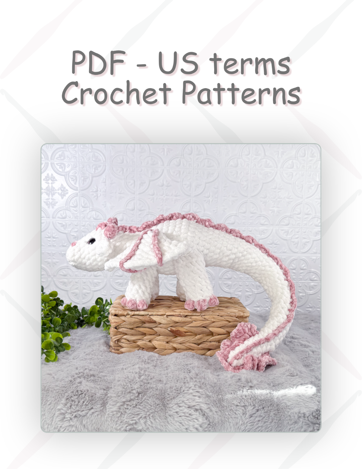 A crochet dragon pattern cover featuring a crocheted white dragon with pink trim standing on a woven basket, with the text 'PDF - US terms Crochet Patterns' above it on a white background.