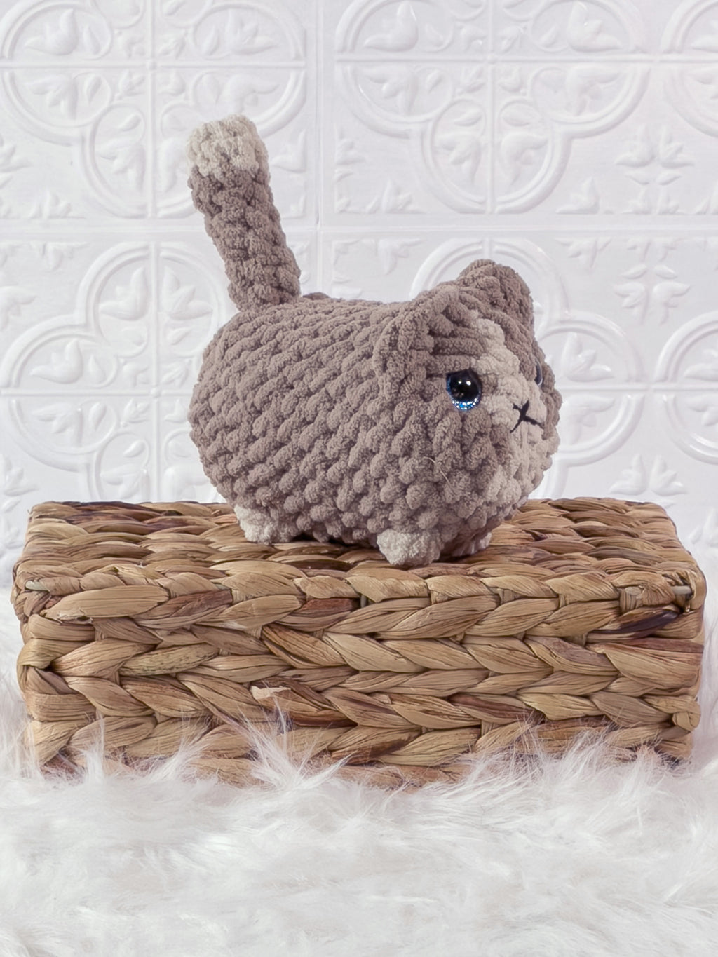 Handmade beige loaf cat crochet plushie shown from an angled view