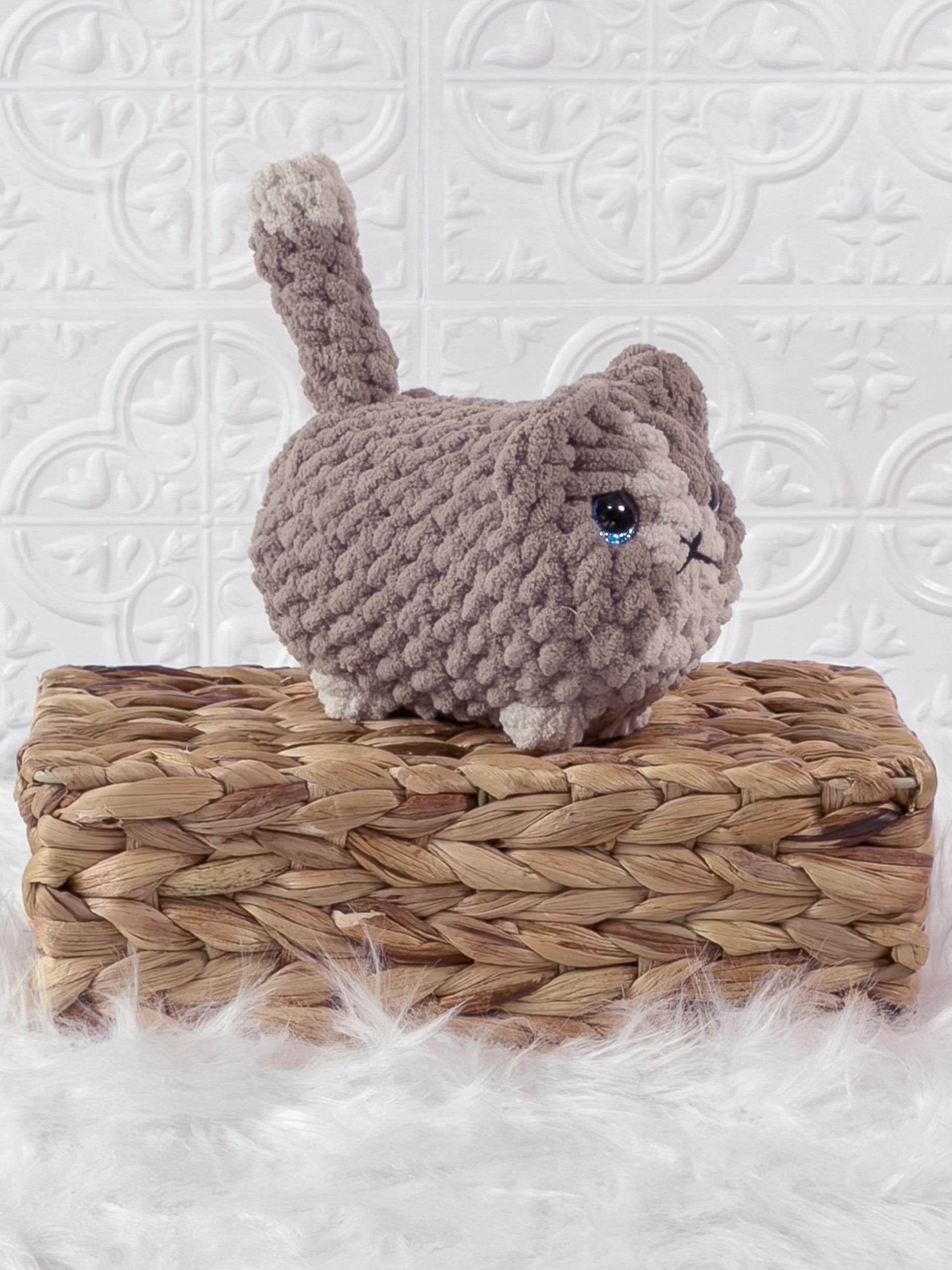 Handmade beige loaf cat crochet plushie shown from an angled view