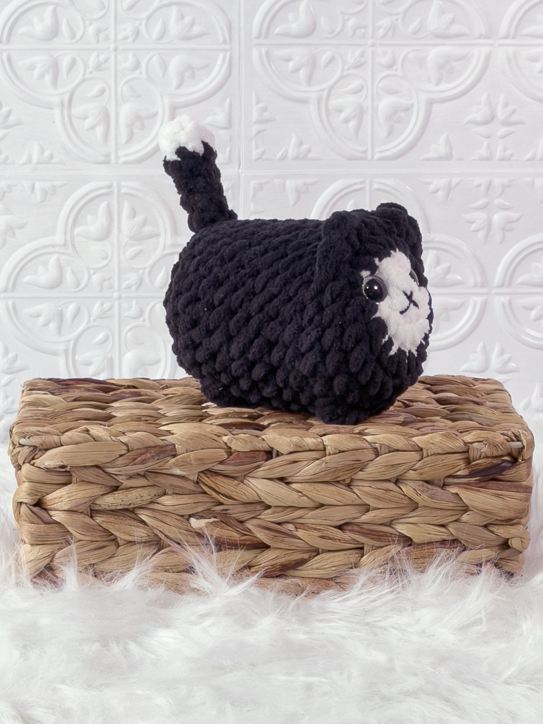 Handmade black loaf cat crochet plushie shown from an angled view