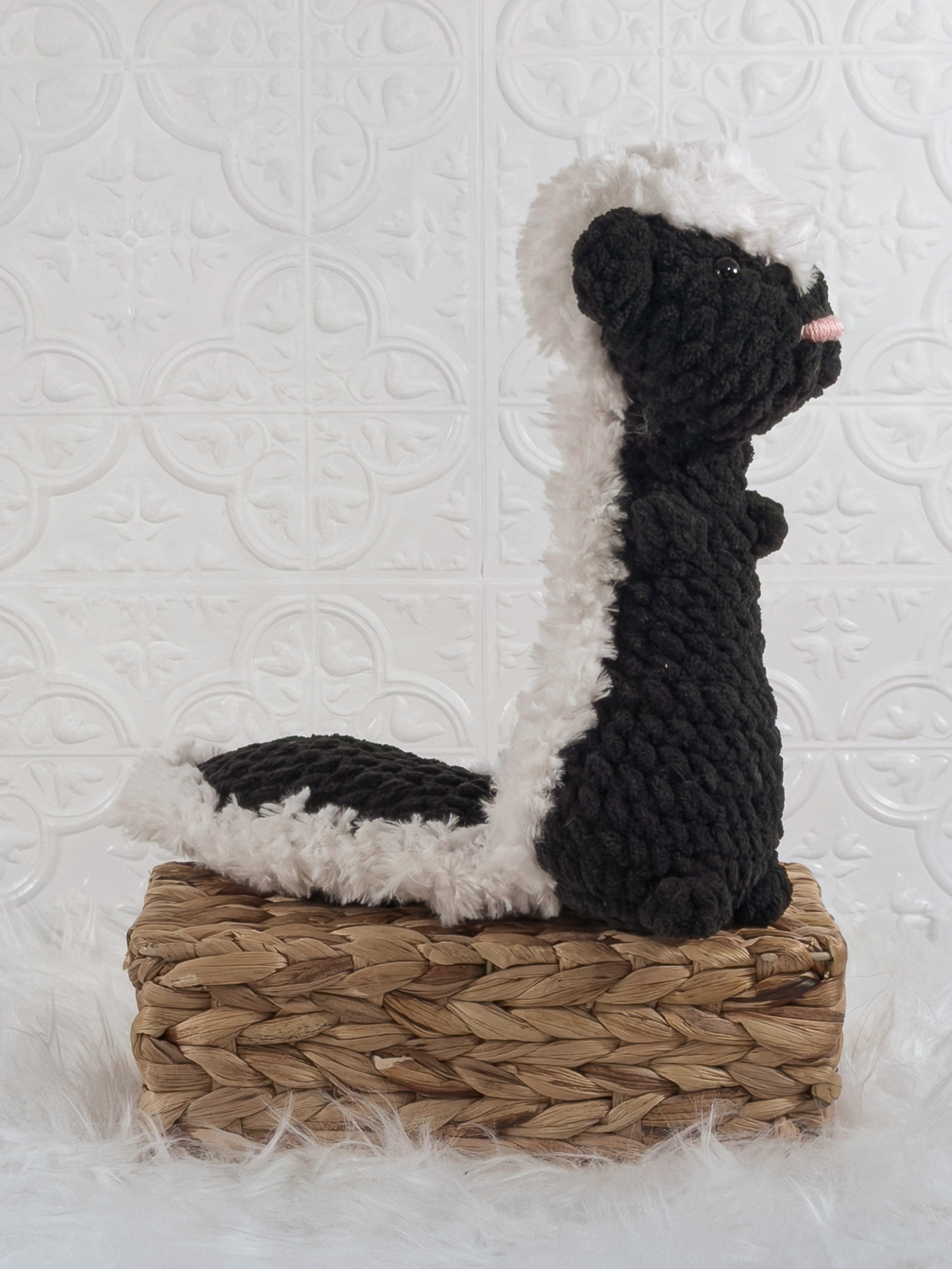 Handmade black skunk crochet plushie shown from an angled view