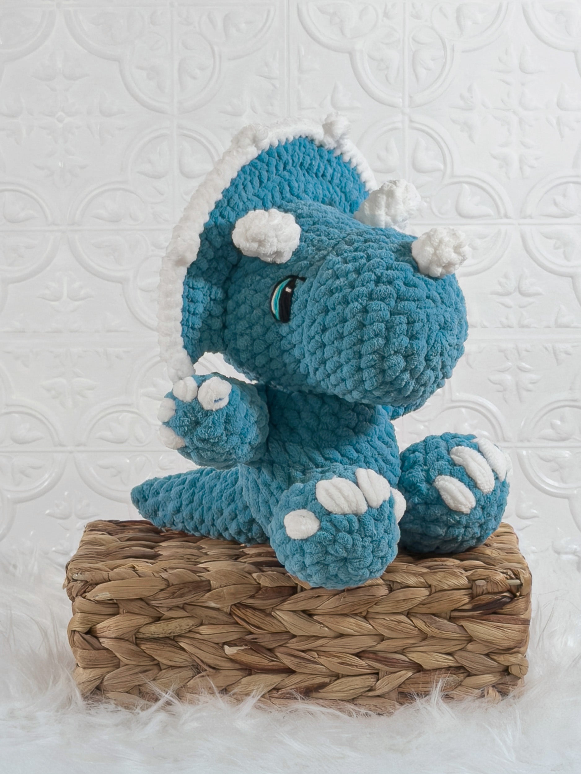 Handmade blue triceratops crochet plushie shown from an angled view