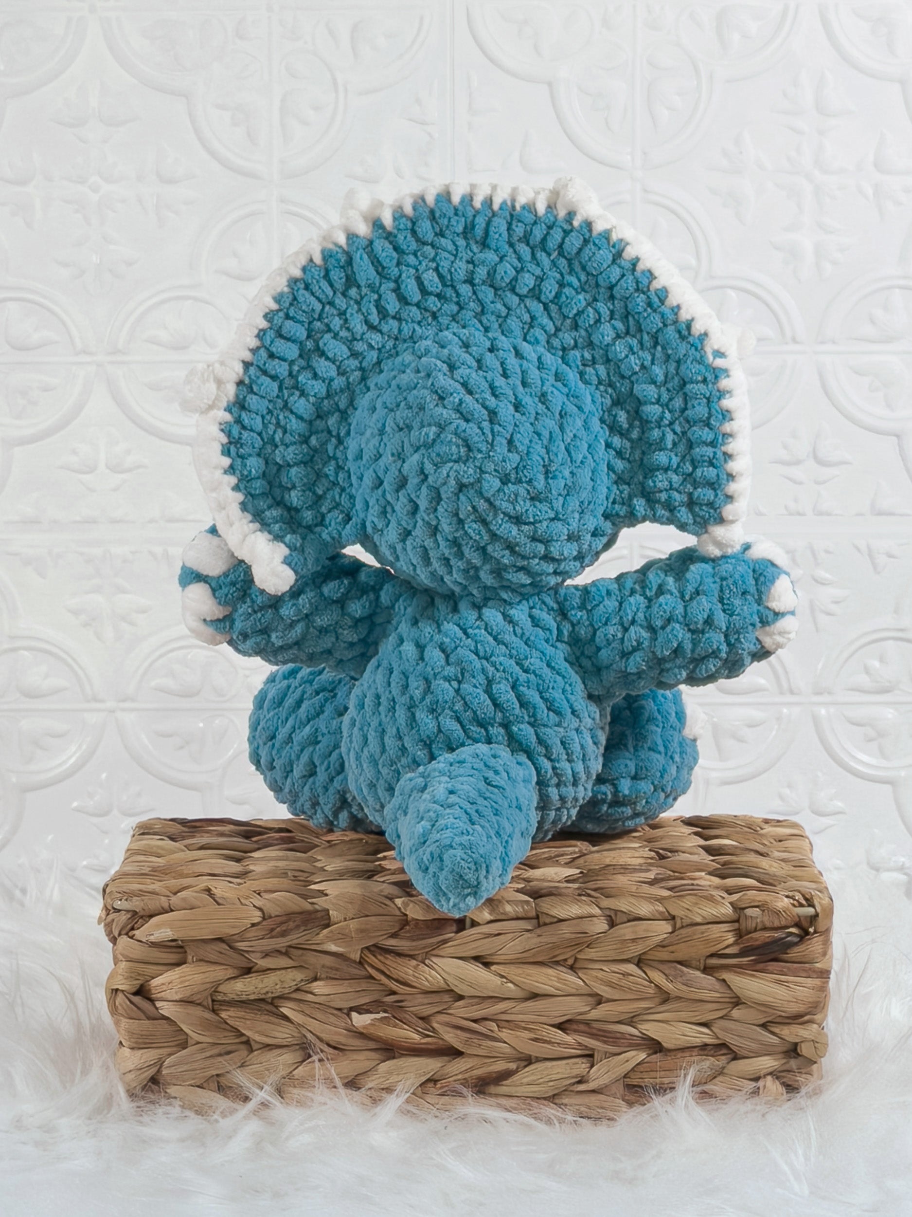 Handmade blue triceratops crochet plushie shown from the back