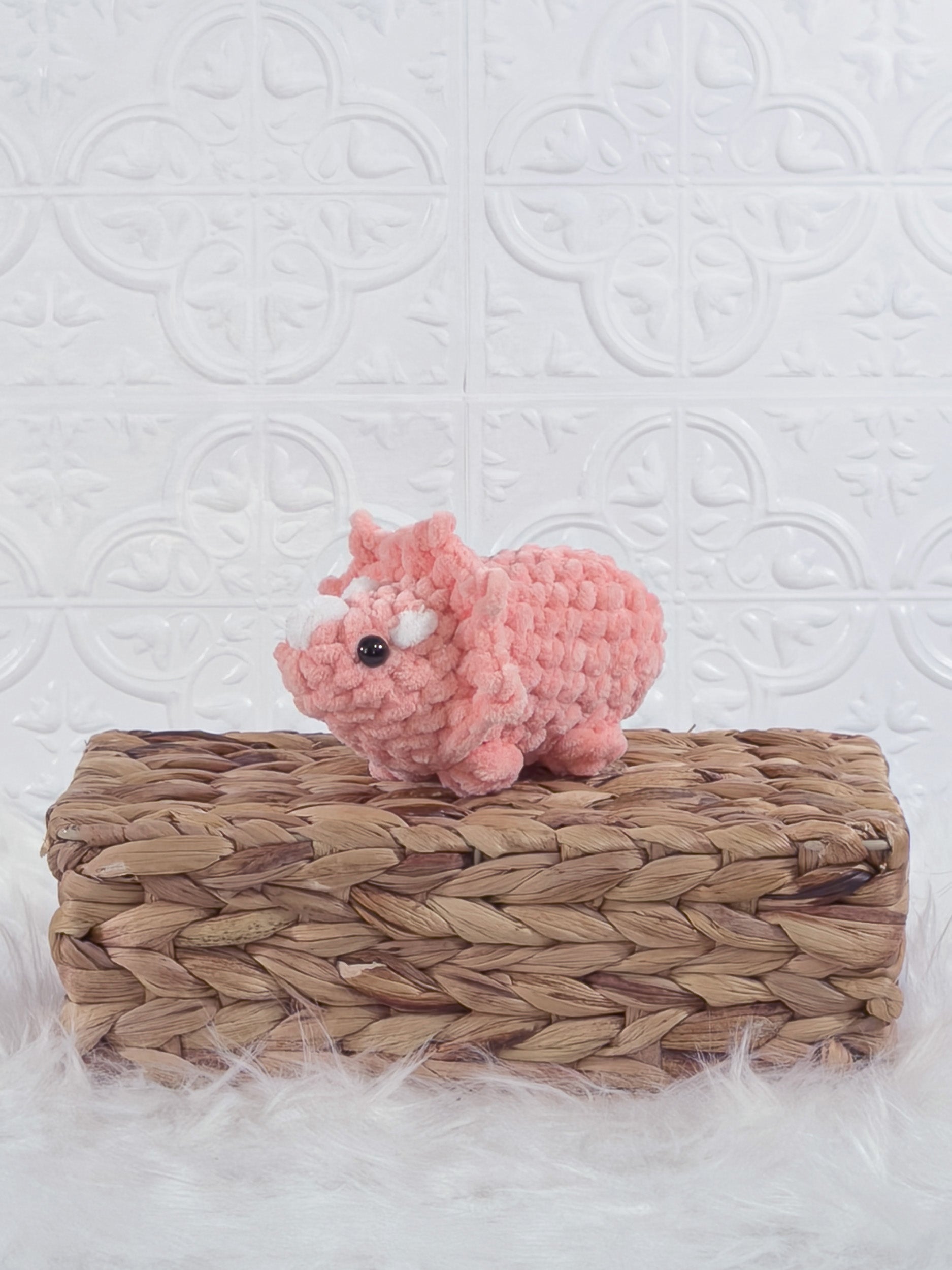 Handmade coral triceratops crochet plushie shown from an angled view