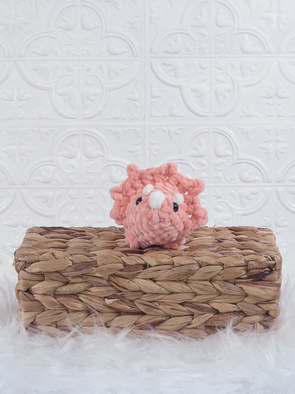 Handmade coral triceratops crochet plushie shown from the front
