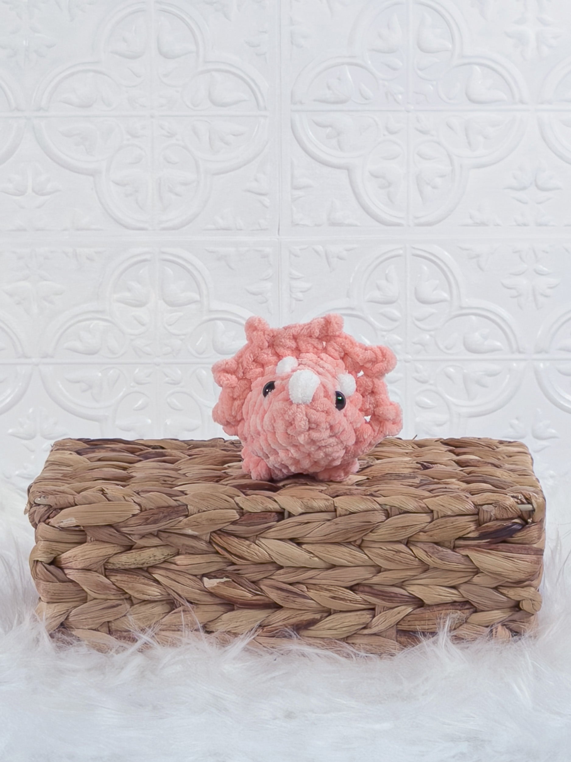 Handmade coral triceratops crochet plushie shown from the front