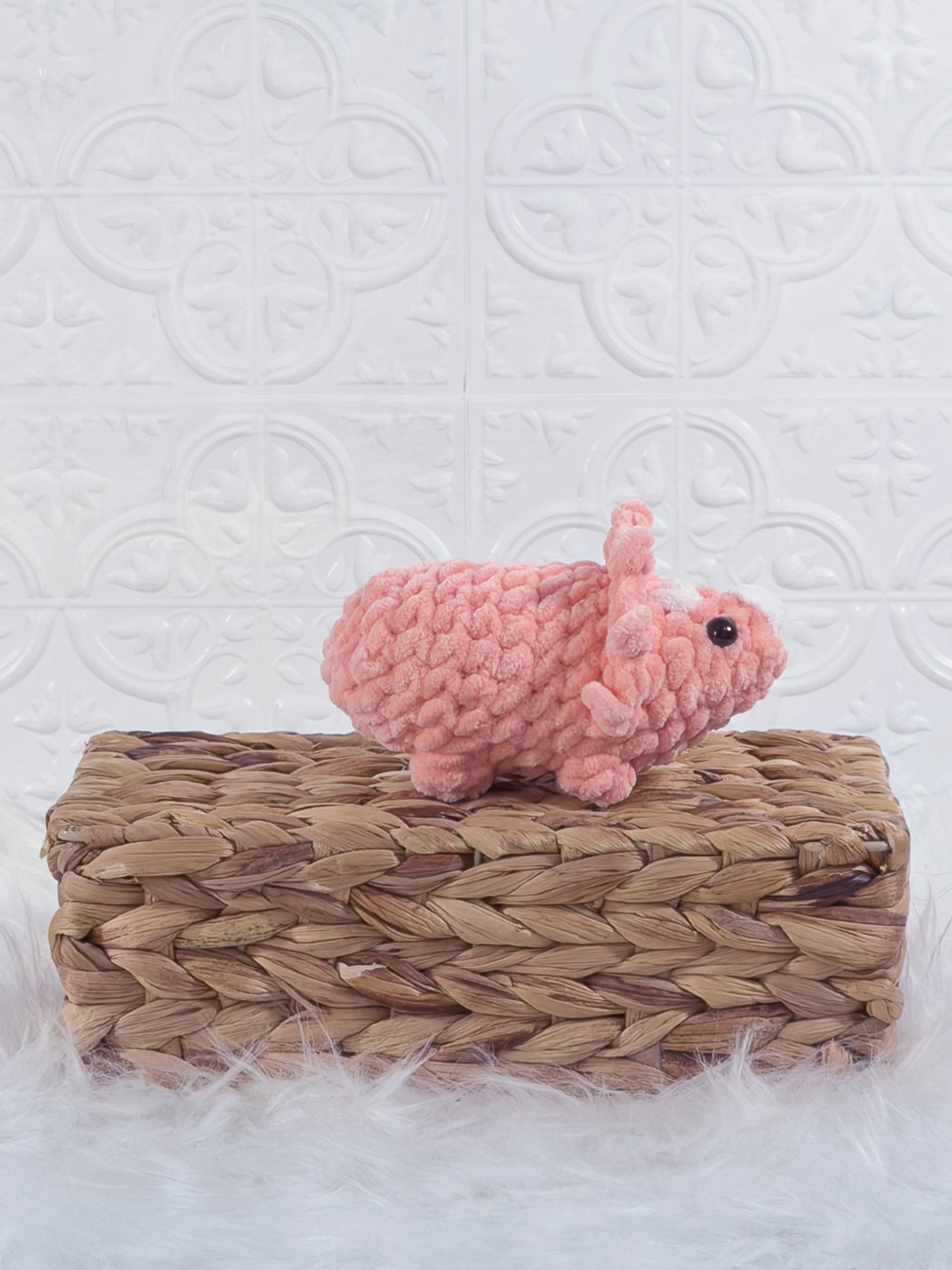 Handmade coral triceratops crochet plushie shown from the side