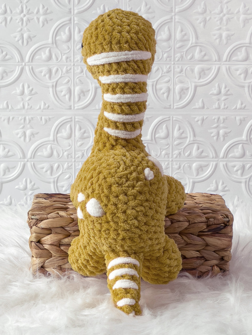 Handmade gold brachiosaurus crochet plushie shown from the back