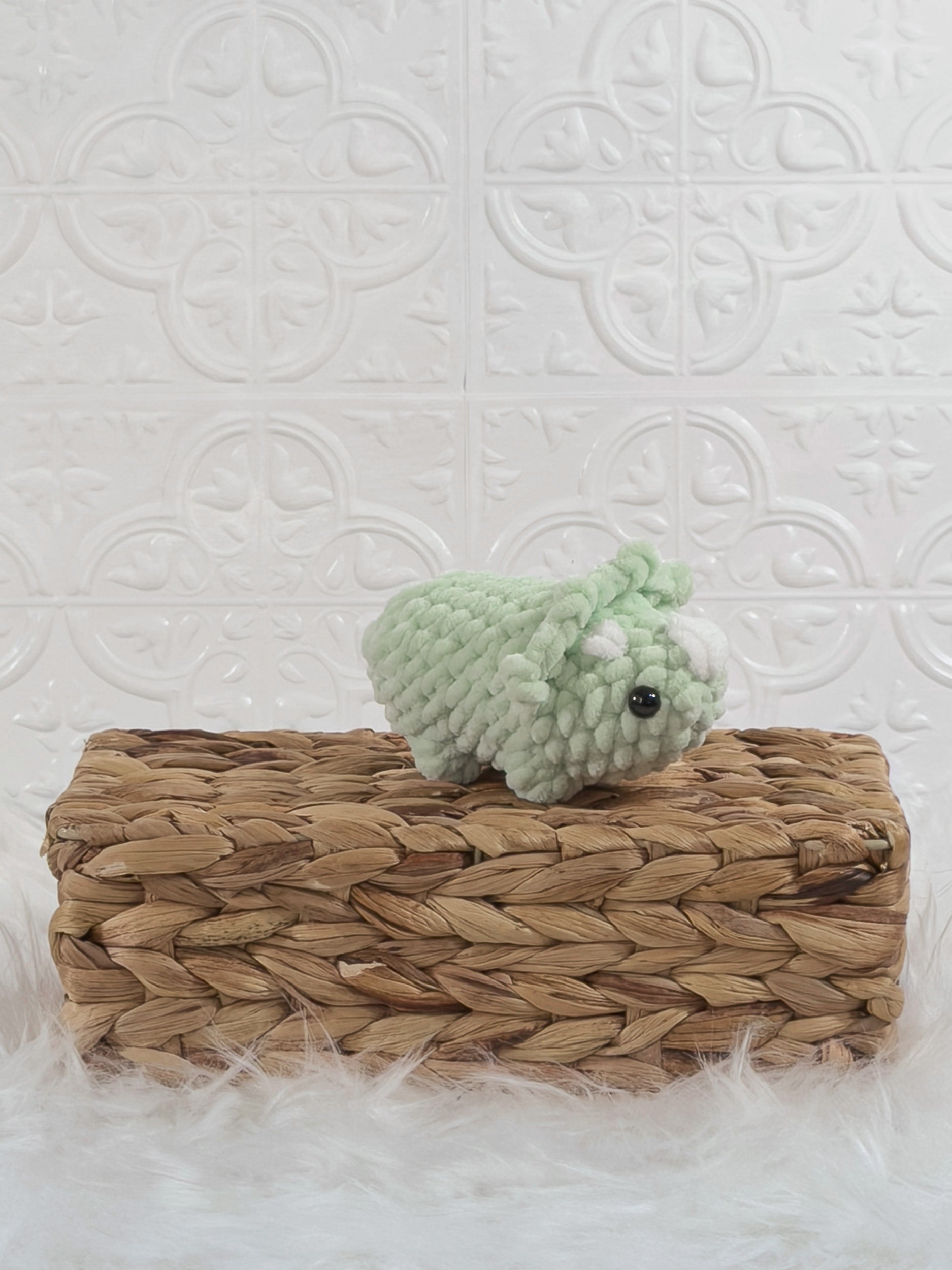 Handmade green triceratops crochet plushie shown from an angled view