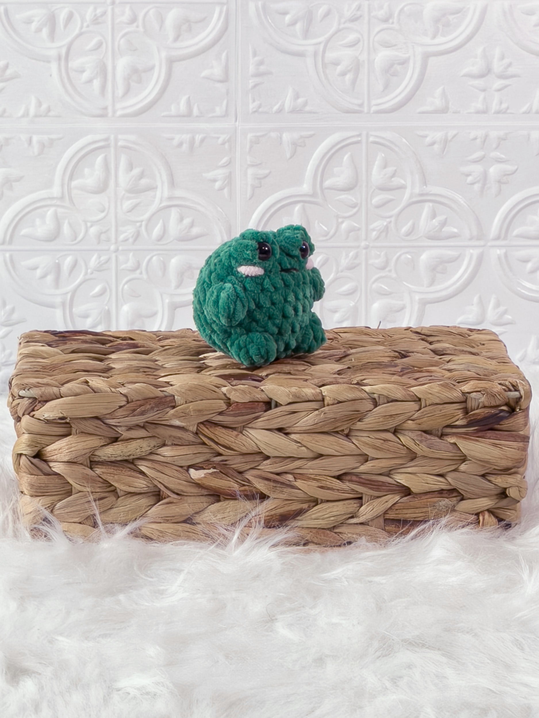 Handmade green, dark mini frog crochet plushie shown from an angled view