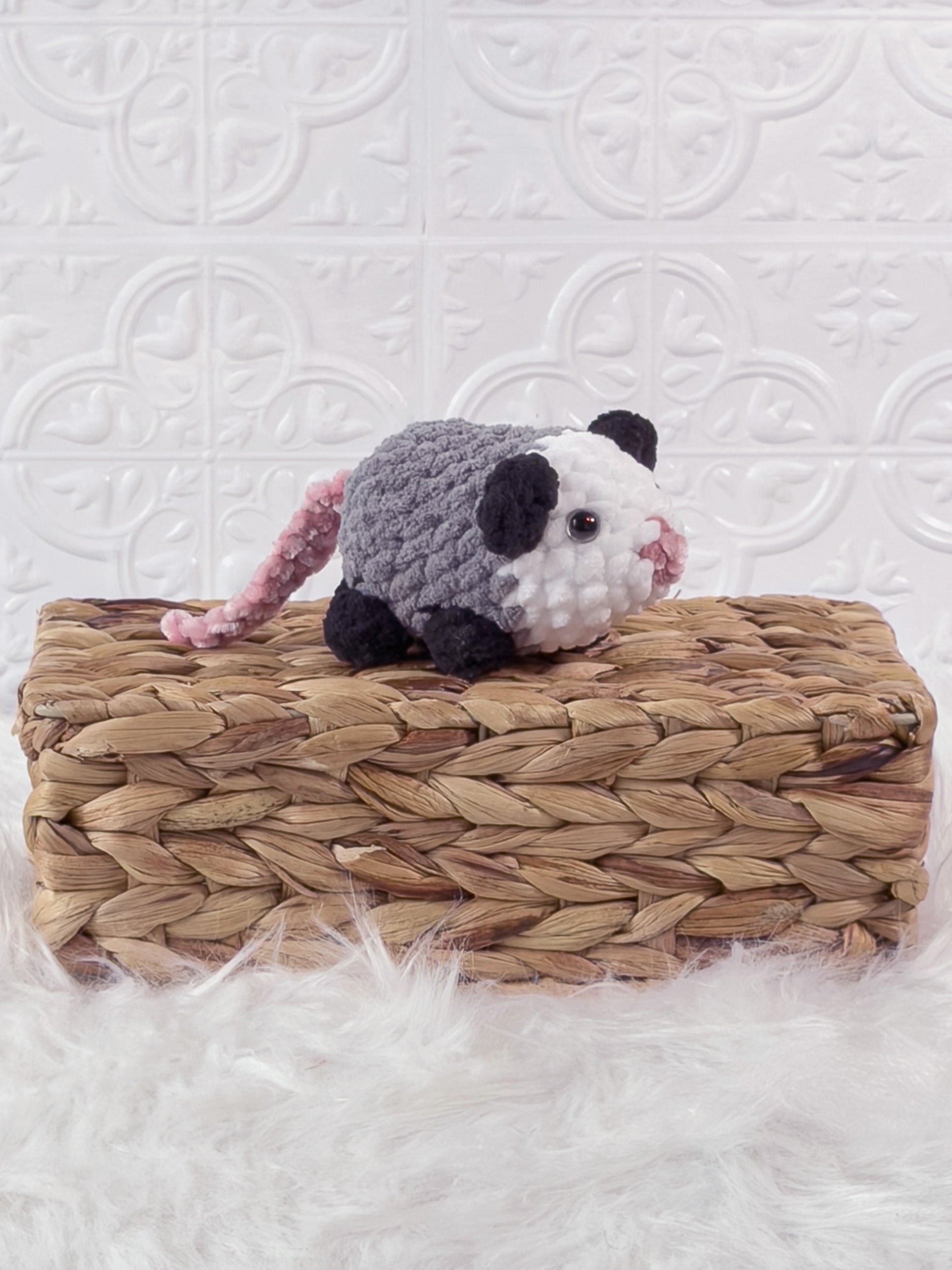 Handmade grey opossum crochet plushie shown from an angled view