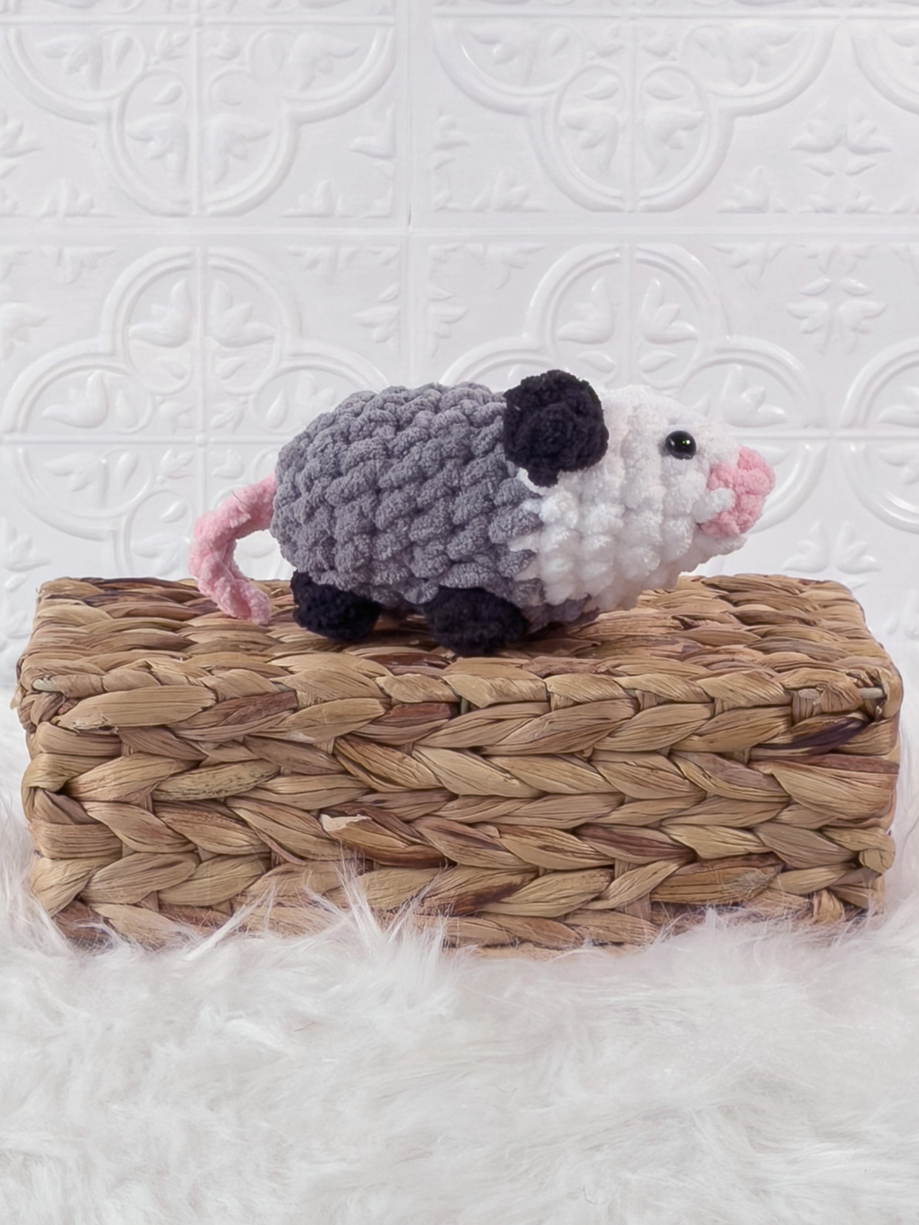 Handmade grey opossum crochet plushie shown from an angled view