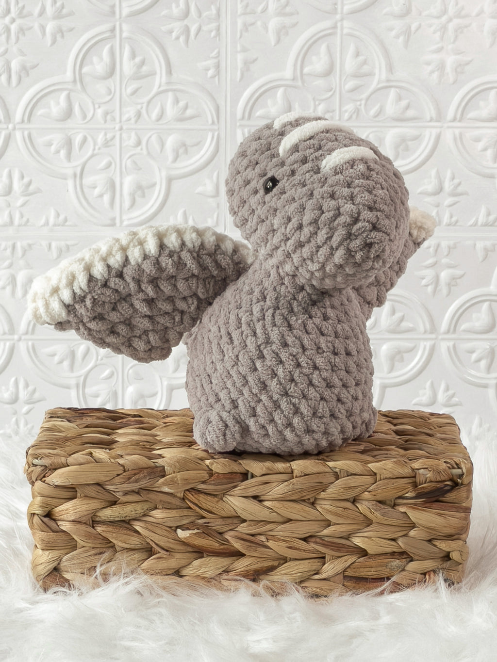 Handmade grey pterodactyl crochet plushie shown from an angled view
