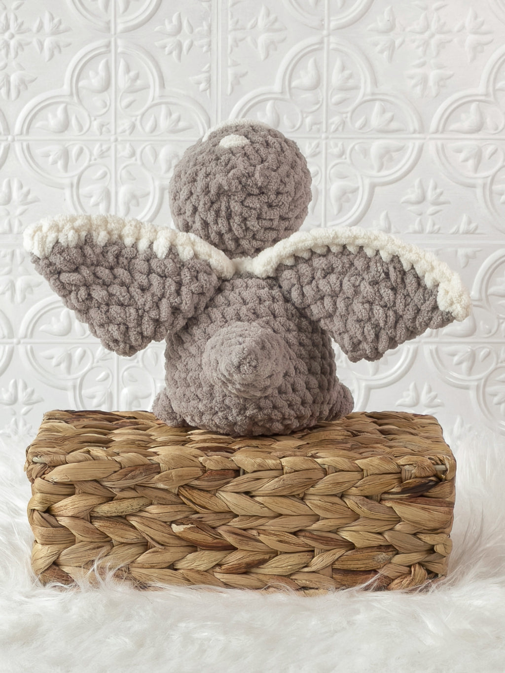 Handmade grey pterodactyl crochet plushie shown from the back