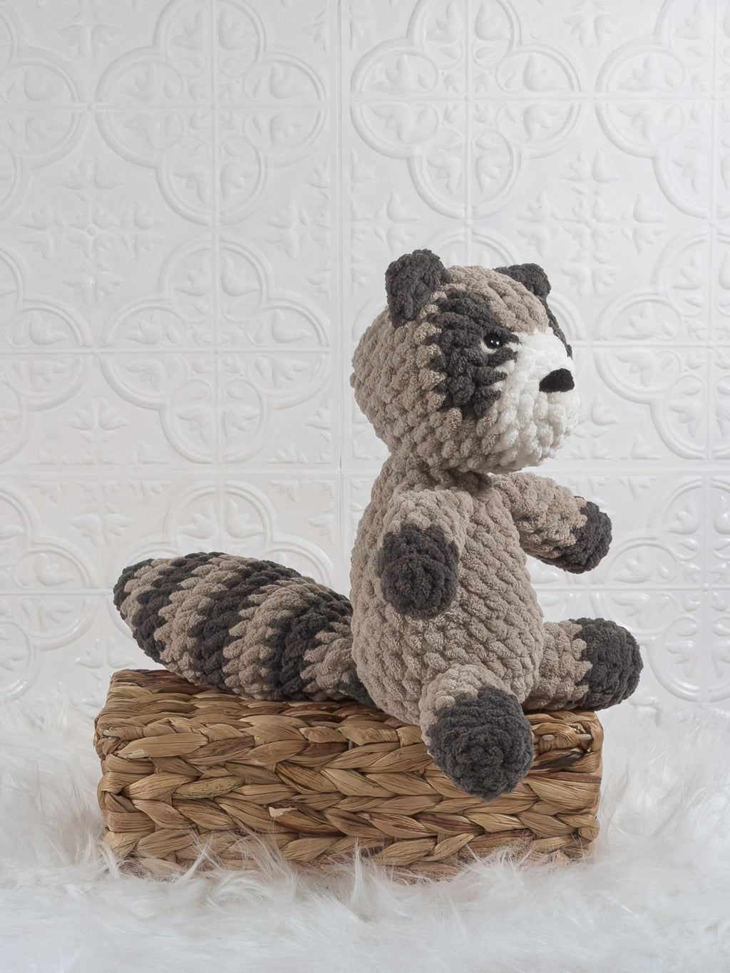 Handmade grey raccoon crochet plushie shown from an angled view