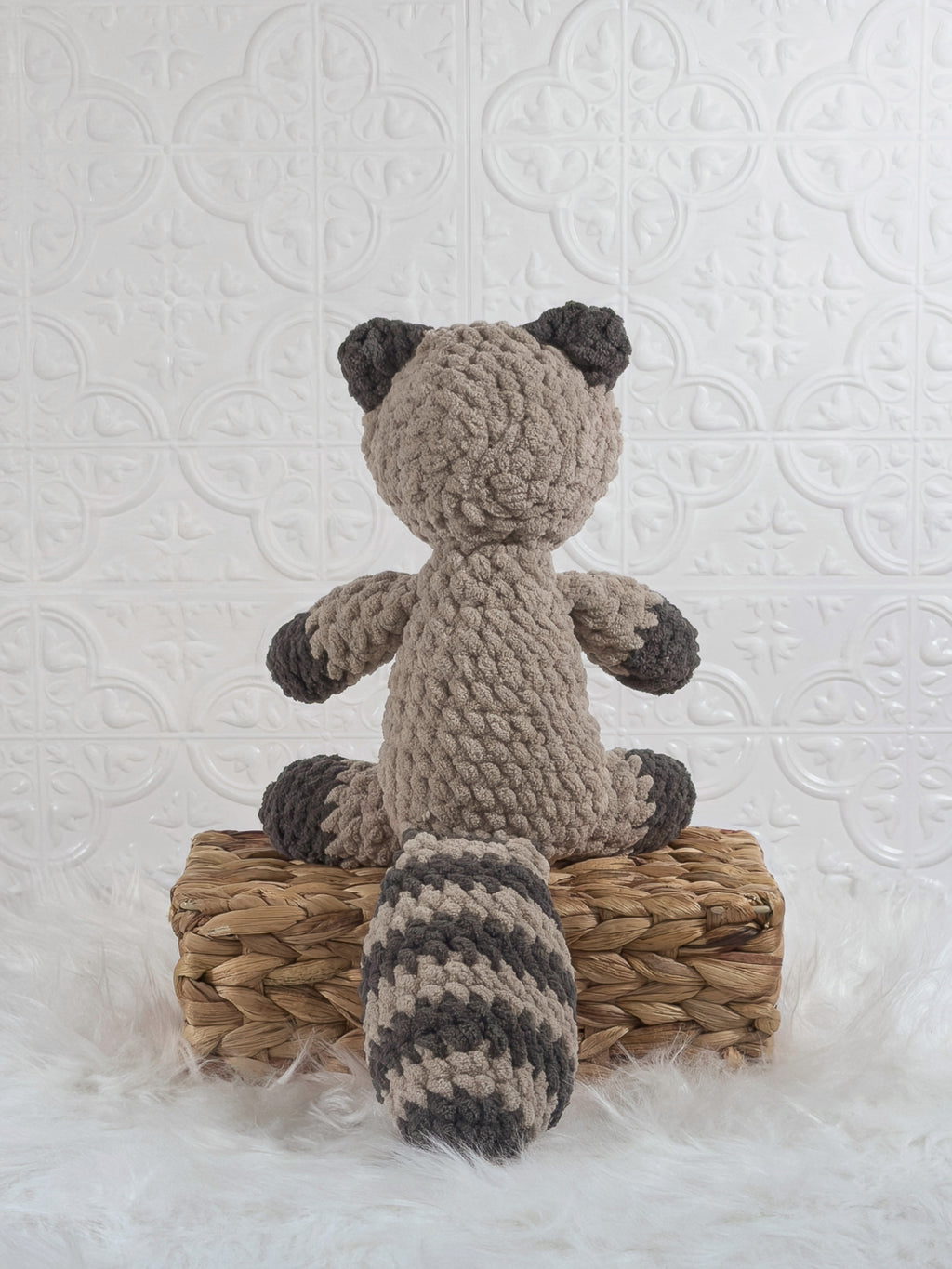 Handmade grey raccoon crochet plushie shown from the back