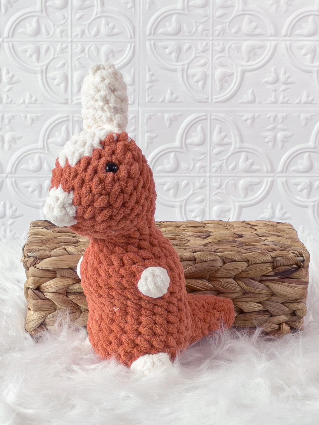 Handmade orange parasaurolophus crochet plushie shown from an angled view