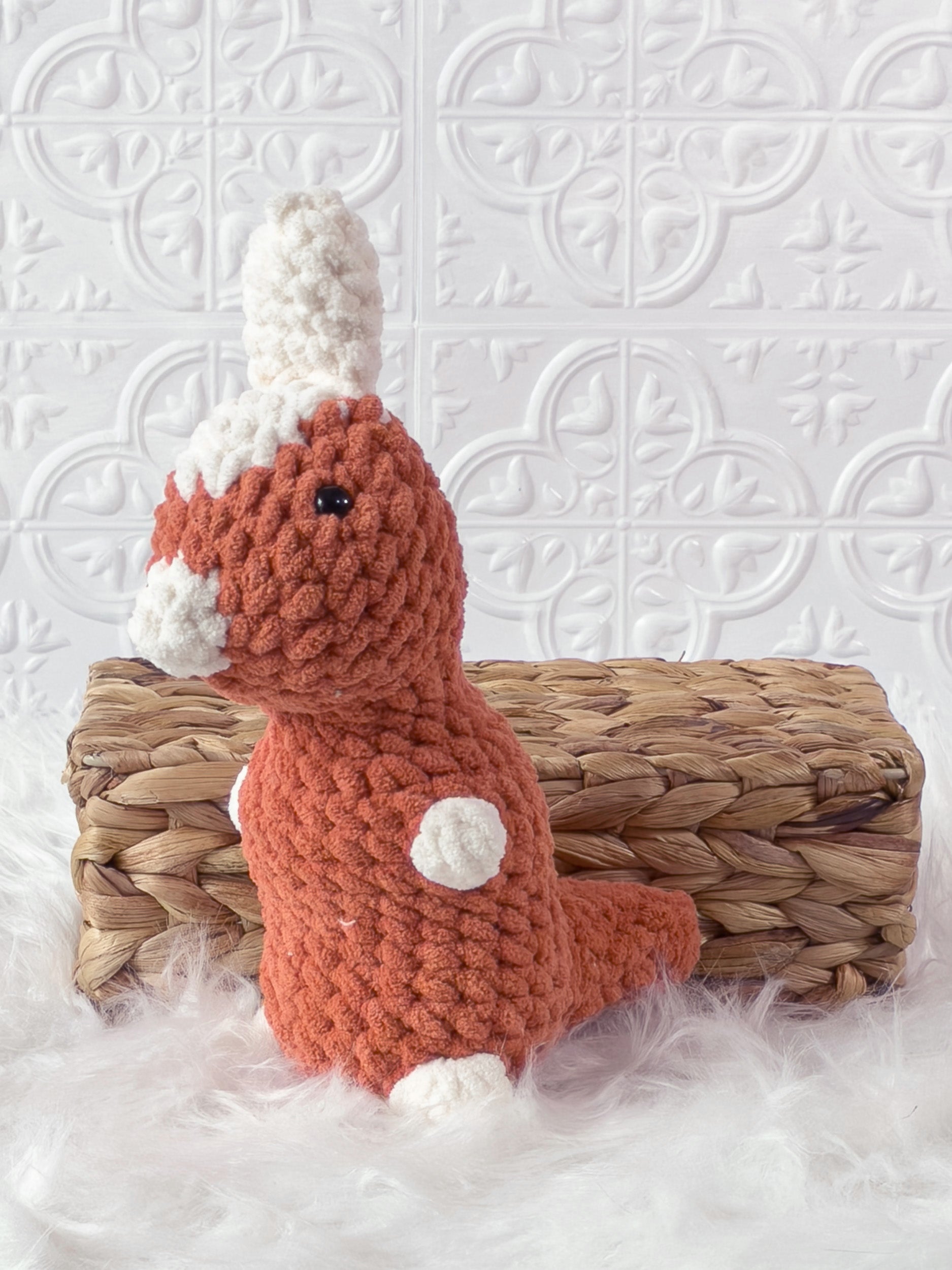 Handmade orange parasaurolophus crochet plushie shown from an angled view