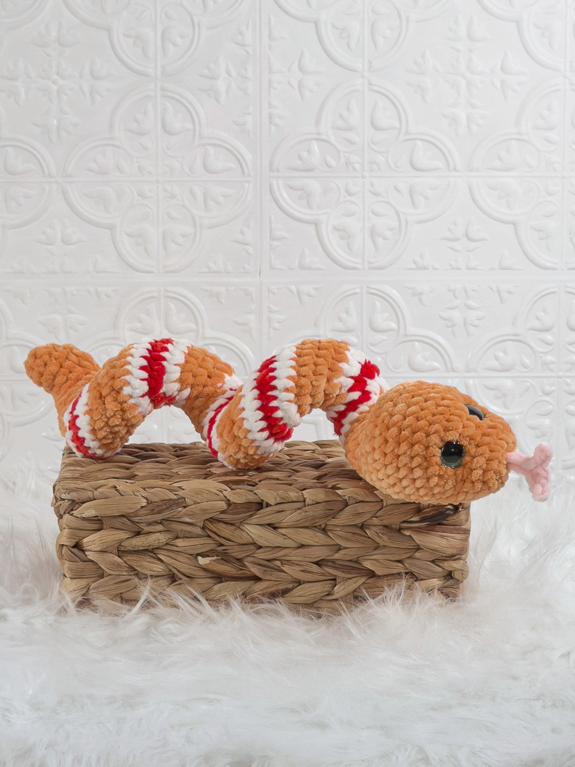 Handmade orange snake crochet plushie shown from an angled view