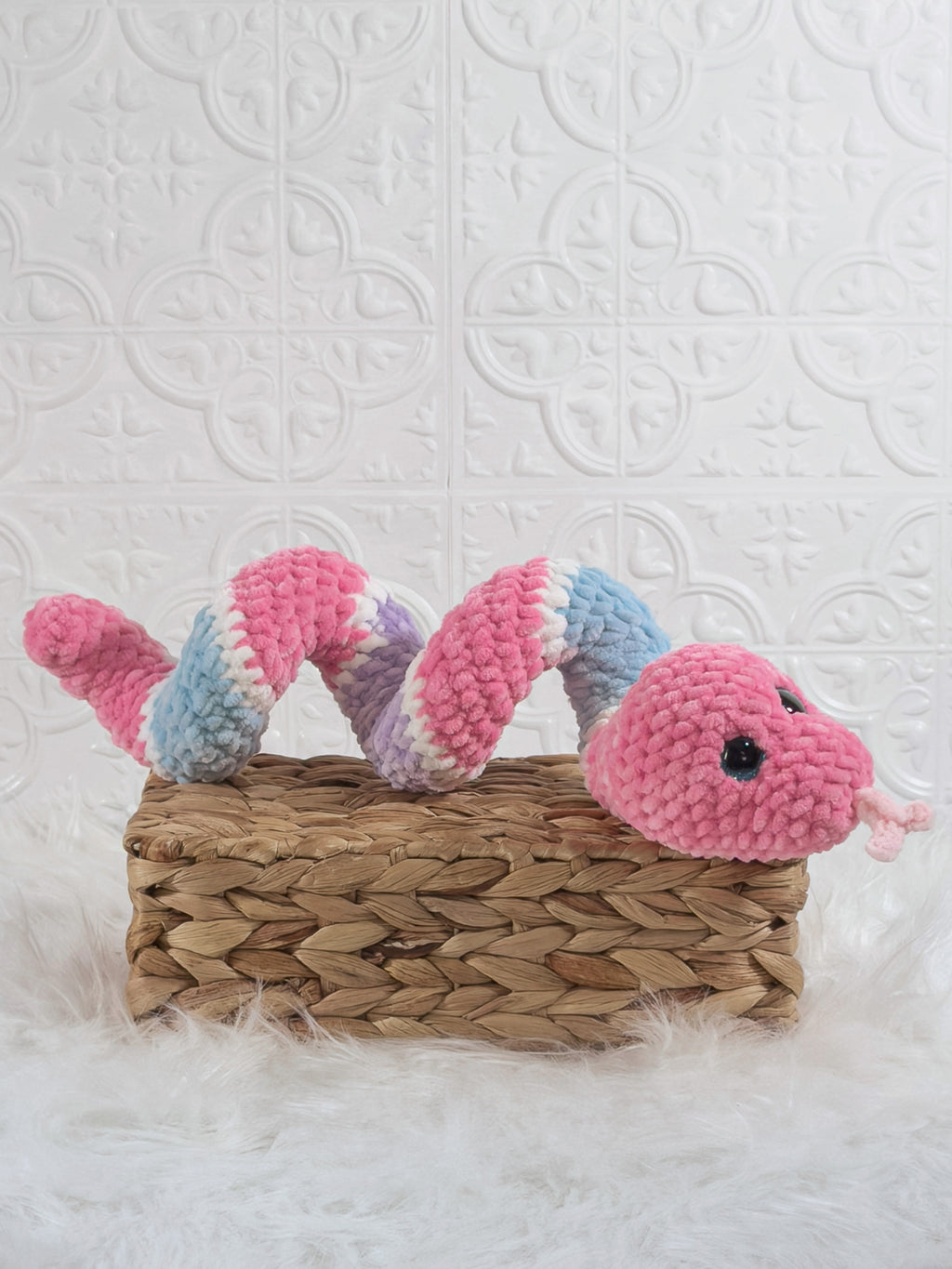 Handmade pink and blue snake crochet plushie shown from an angled view