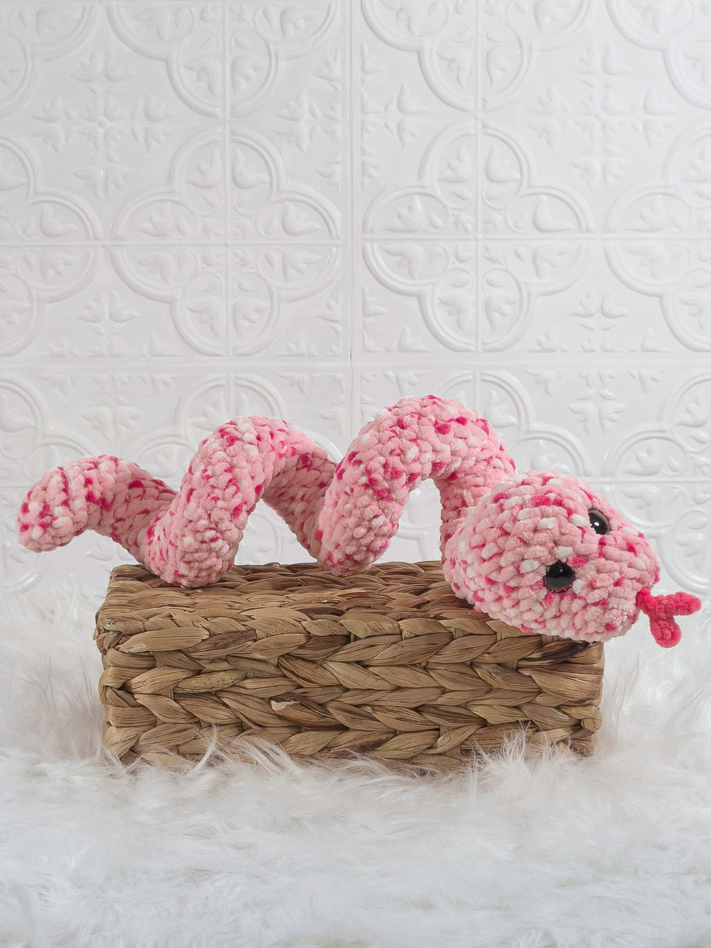 Handmade pink speckle snake crochet plushie shown from an angled view