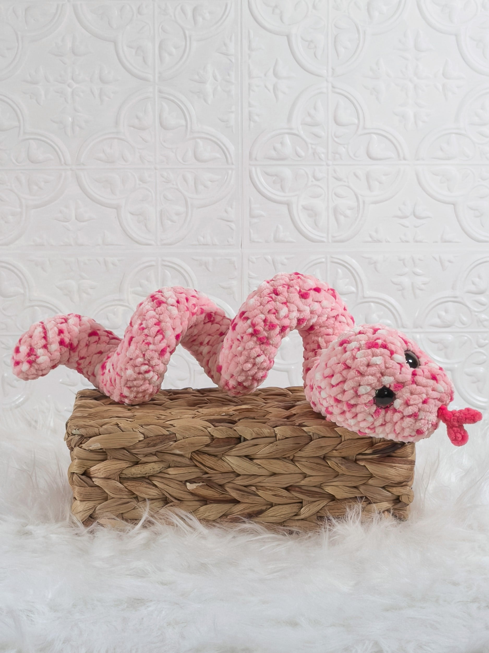 Handmade pink speckle snake crochet plushie shown from an angled view