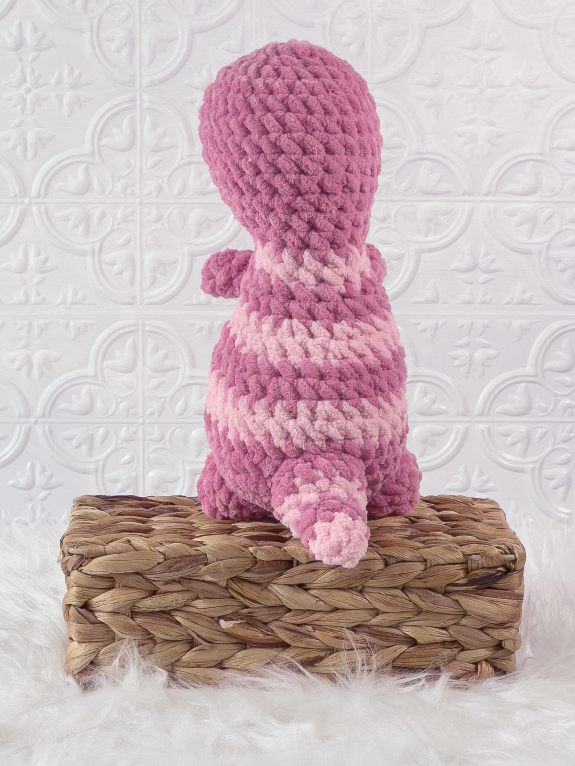 Handmade pink t rex crochet plushie shown from the back