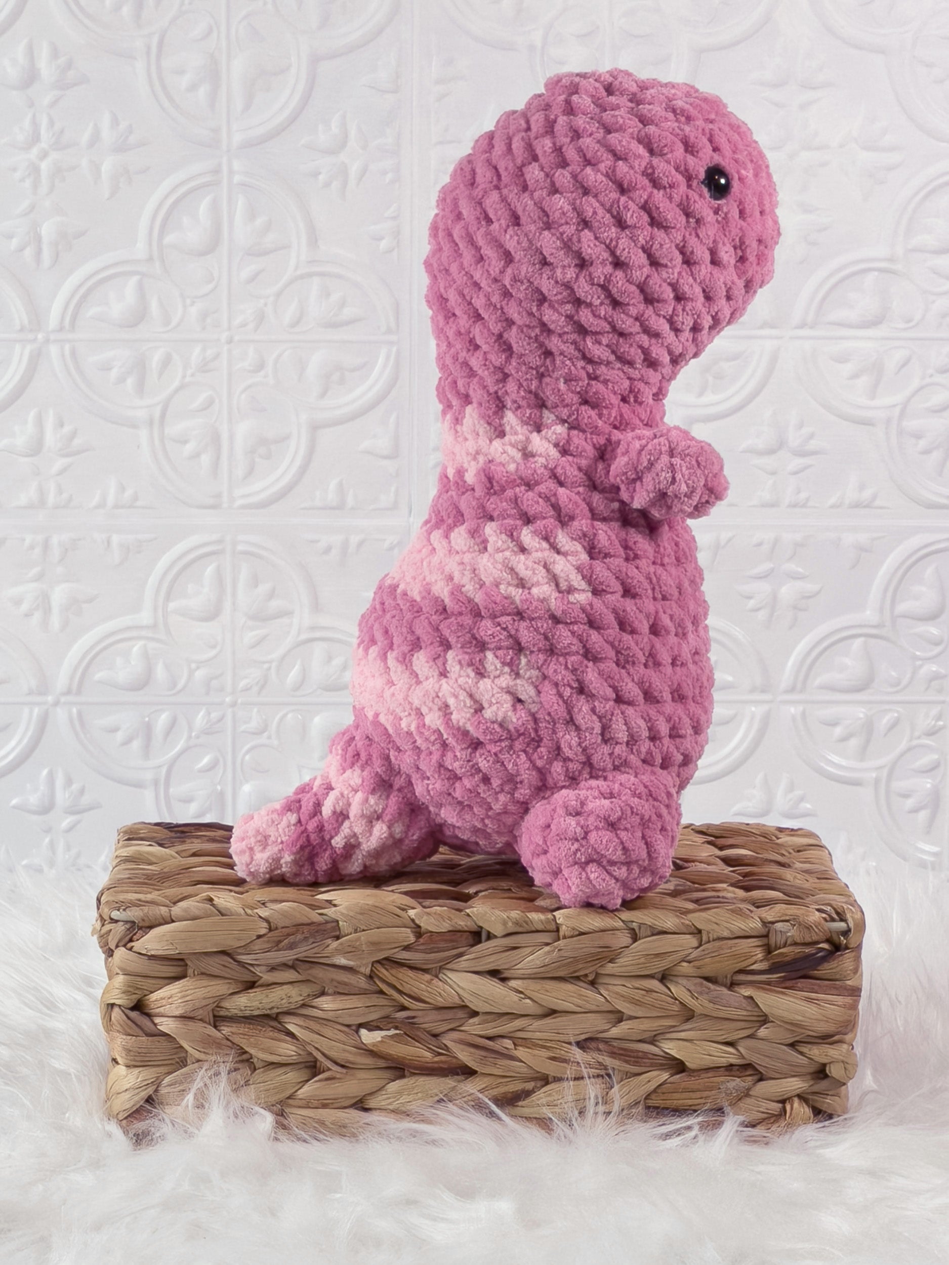 Handmade pink t rex crochet plushie shown from the side