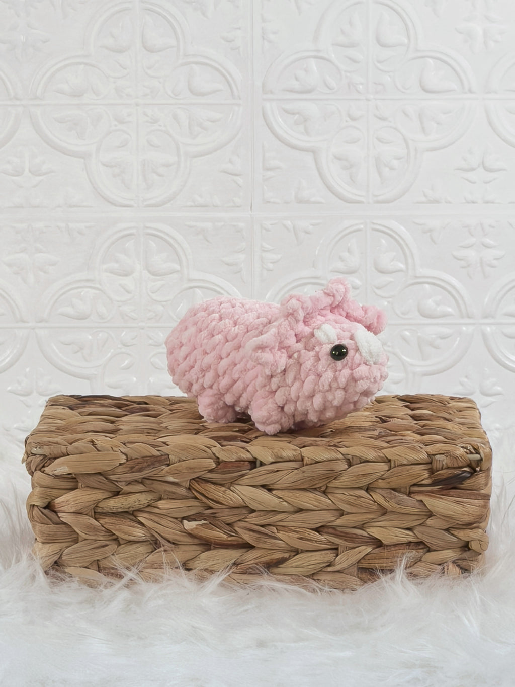 Handmade pink triceratops crochet plushie shown from an angled view