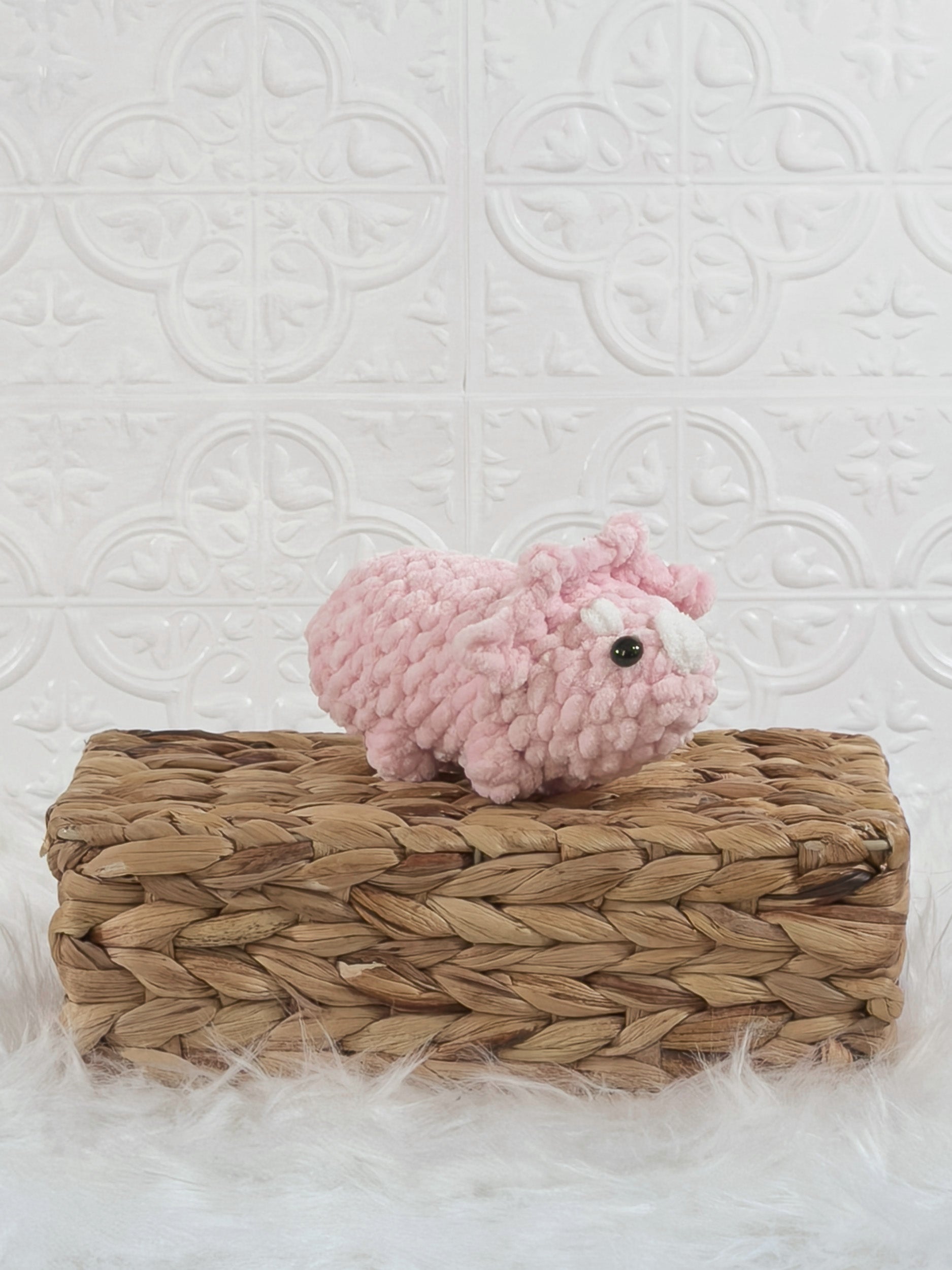 Handmade pink triceratops crochet plushie shown from an angled view