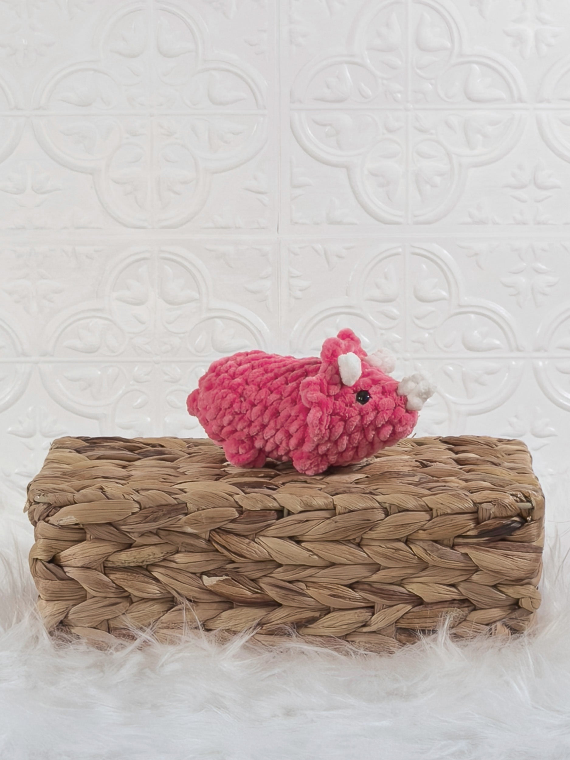 Handmade pink triceratops crochet plushie shown from an angled view