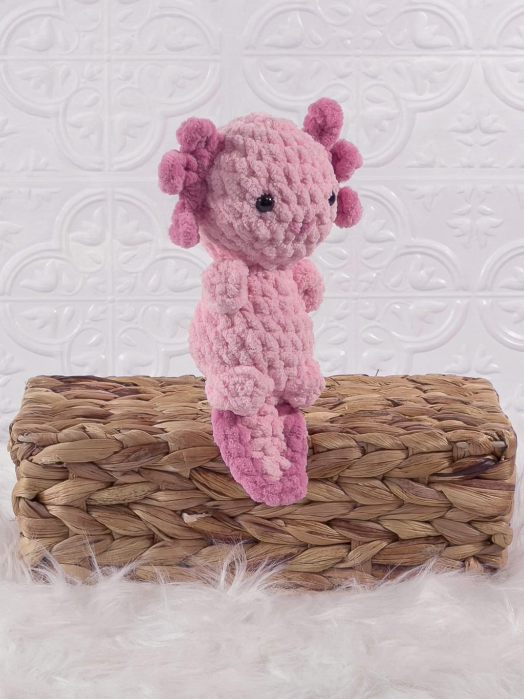 Handmade pink , dark axolotl crochet plushie shown from an angled view