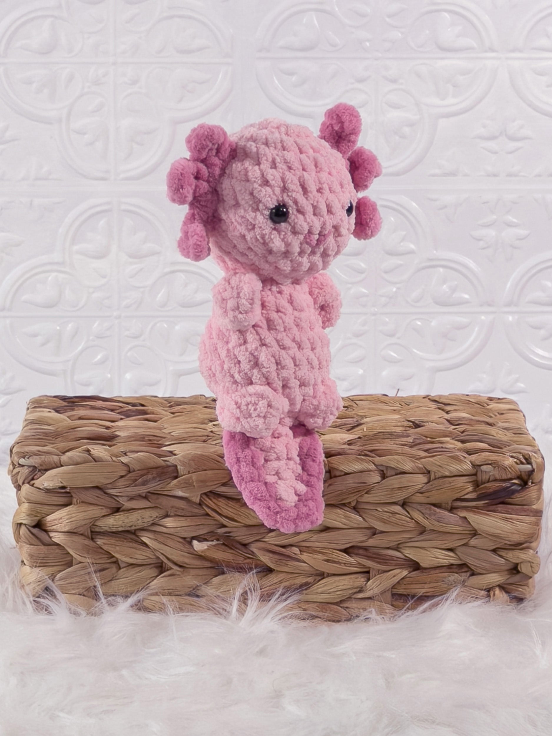 Handmade pink , dark axolotl crochet plushie shown from an angled view