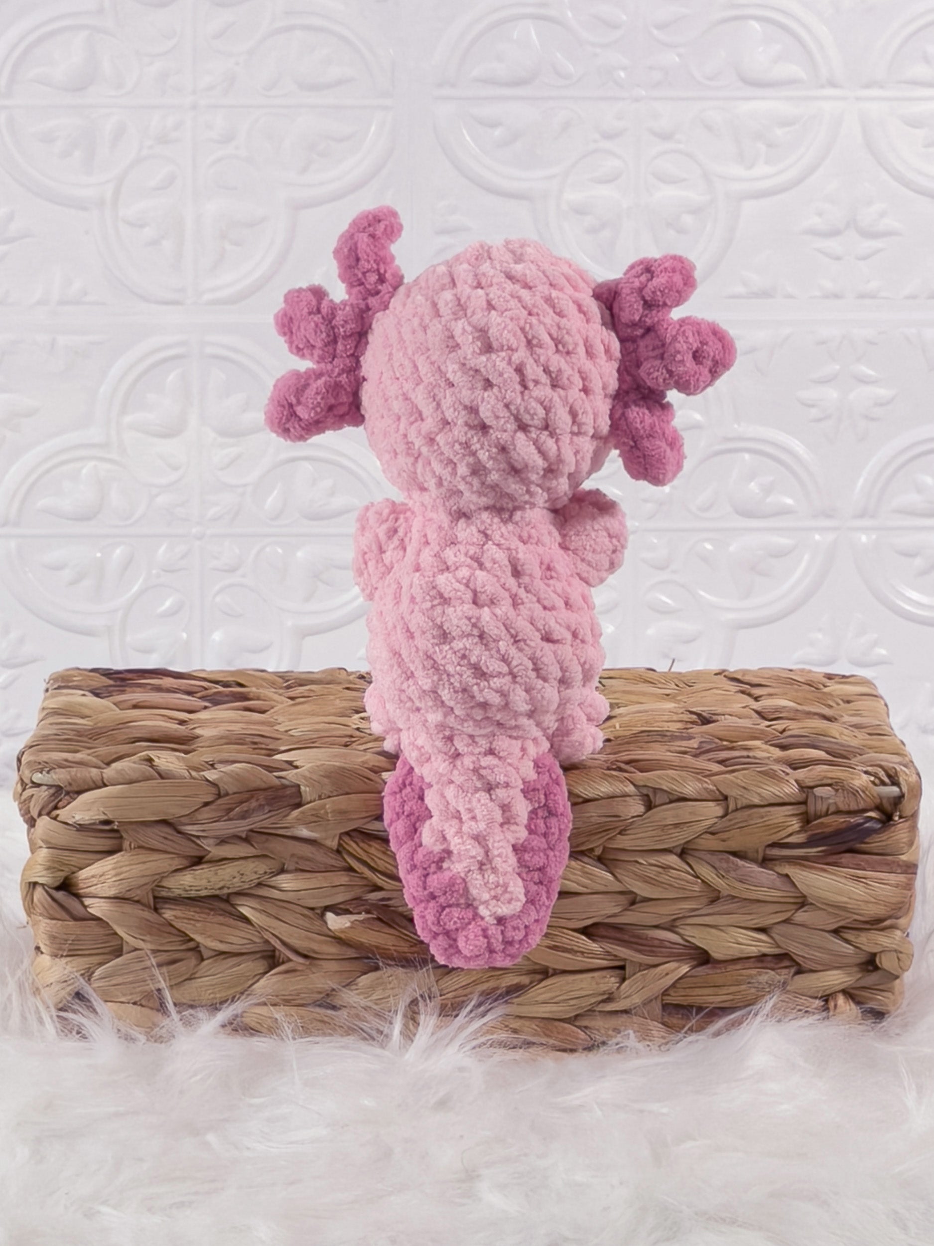 Handmade pink , dark axolotl crochet plushie shown from the back