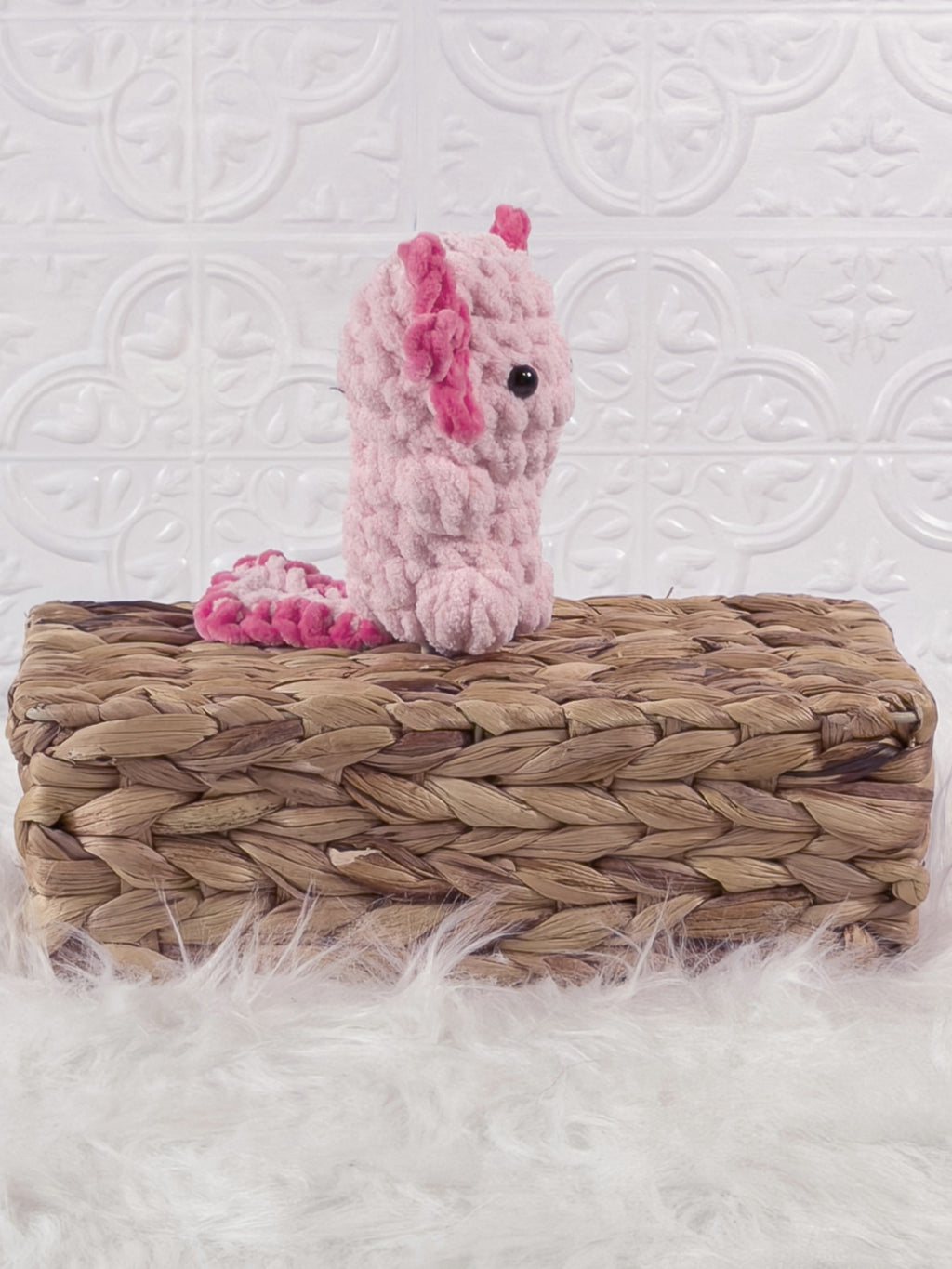 Handmade pink, light axolotl crochet plushie shown from an angled view