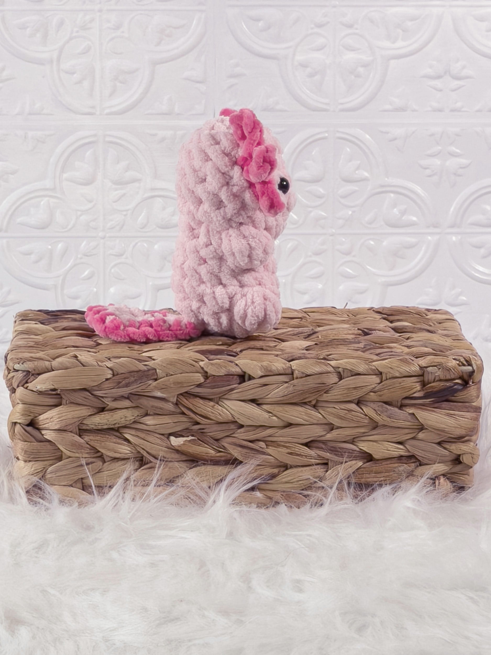 Handmade pink, light axolotl crochet plushie shown from the side
