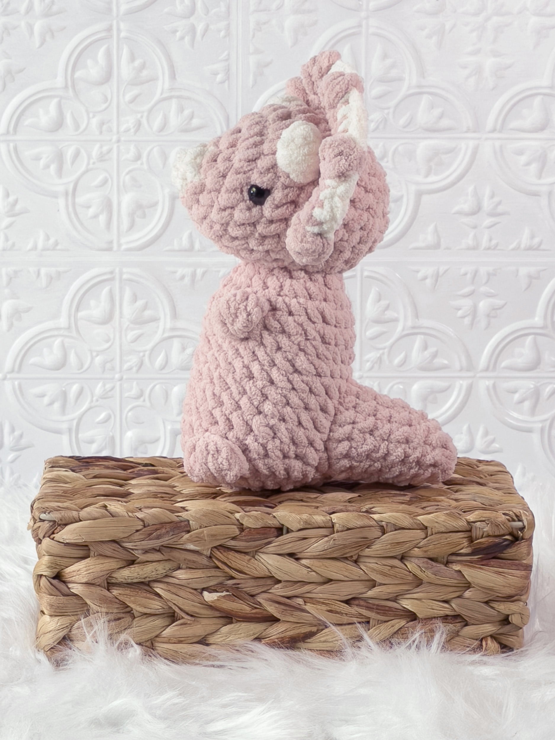 Handmade pink , light triceratops crochet plushie shown from the back