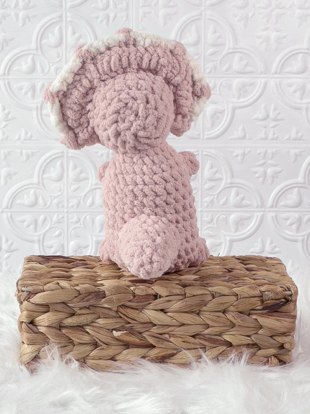 Handmade pink , light triceratops crochet plushie shown from the side