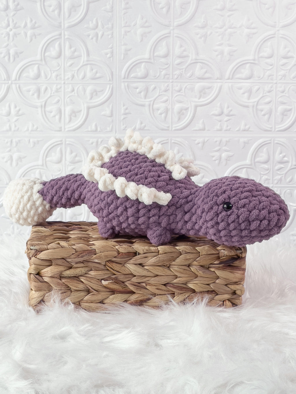 Handmade purple stegosaurus crochet plushie shown from an angled view