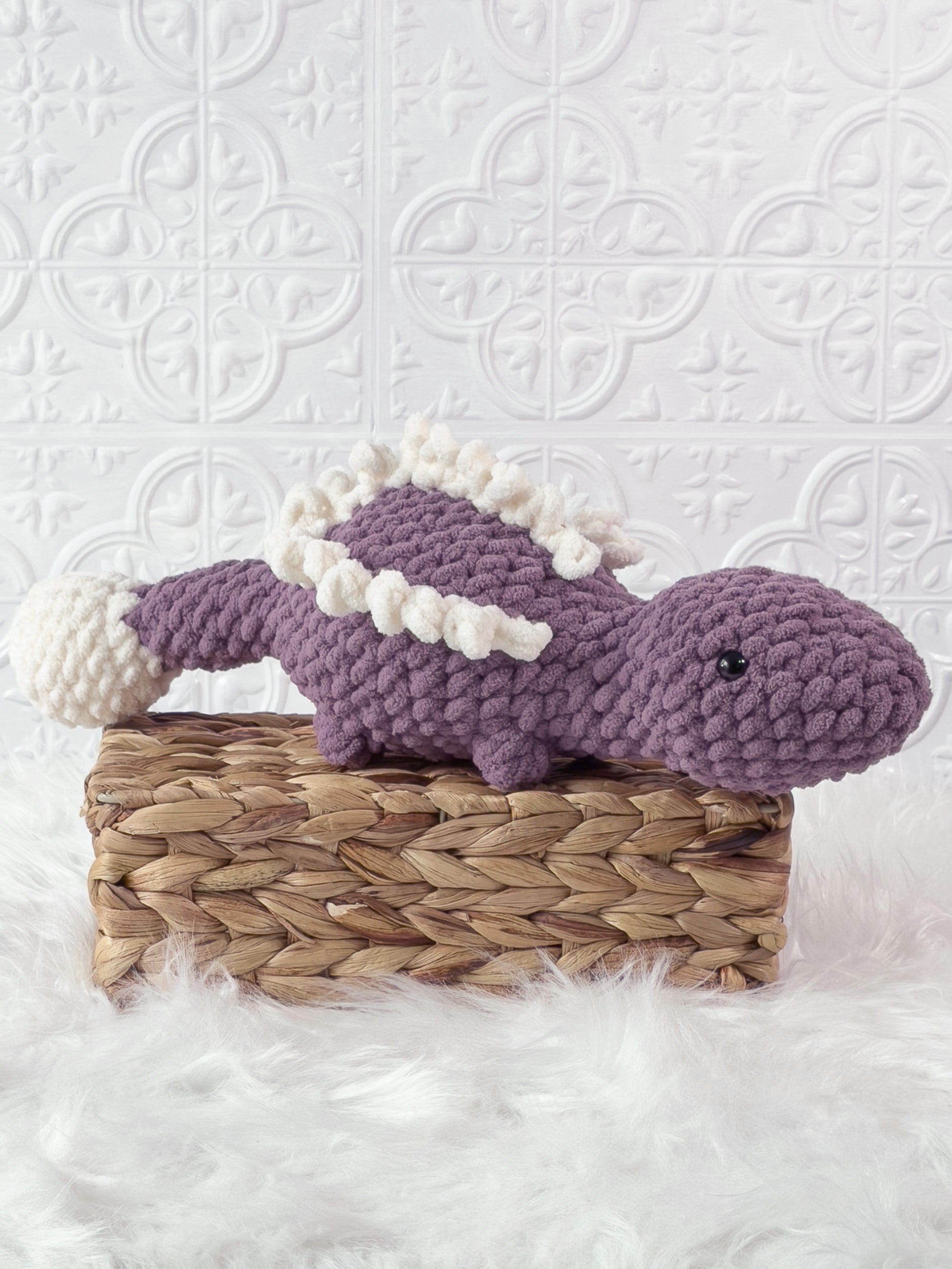 Handmade purple stegosaurus crochet plushie shown from an angled view