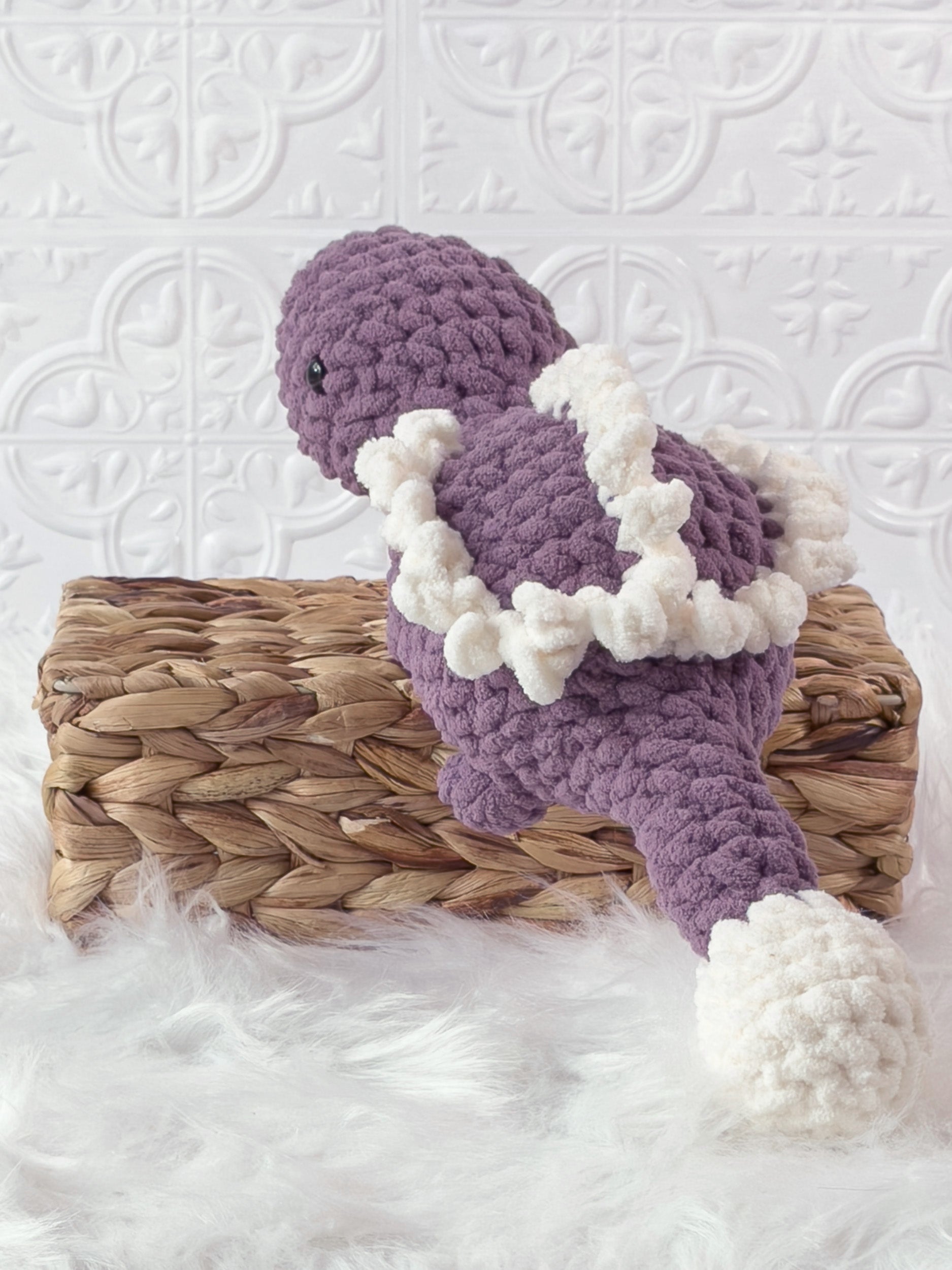 Handmade purple stegosaurus crochet plushie shown from the back