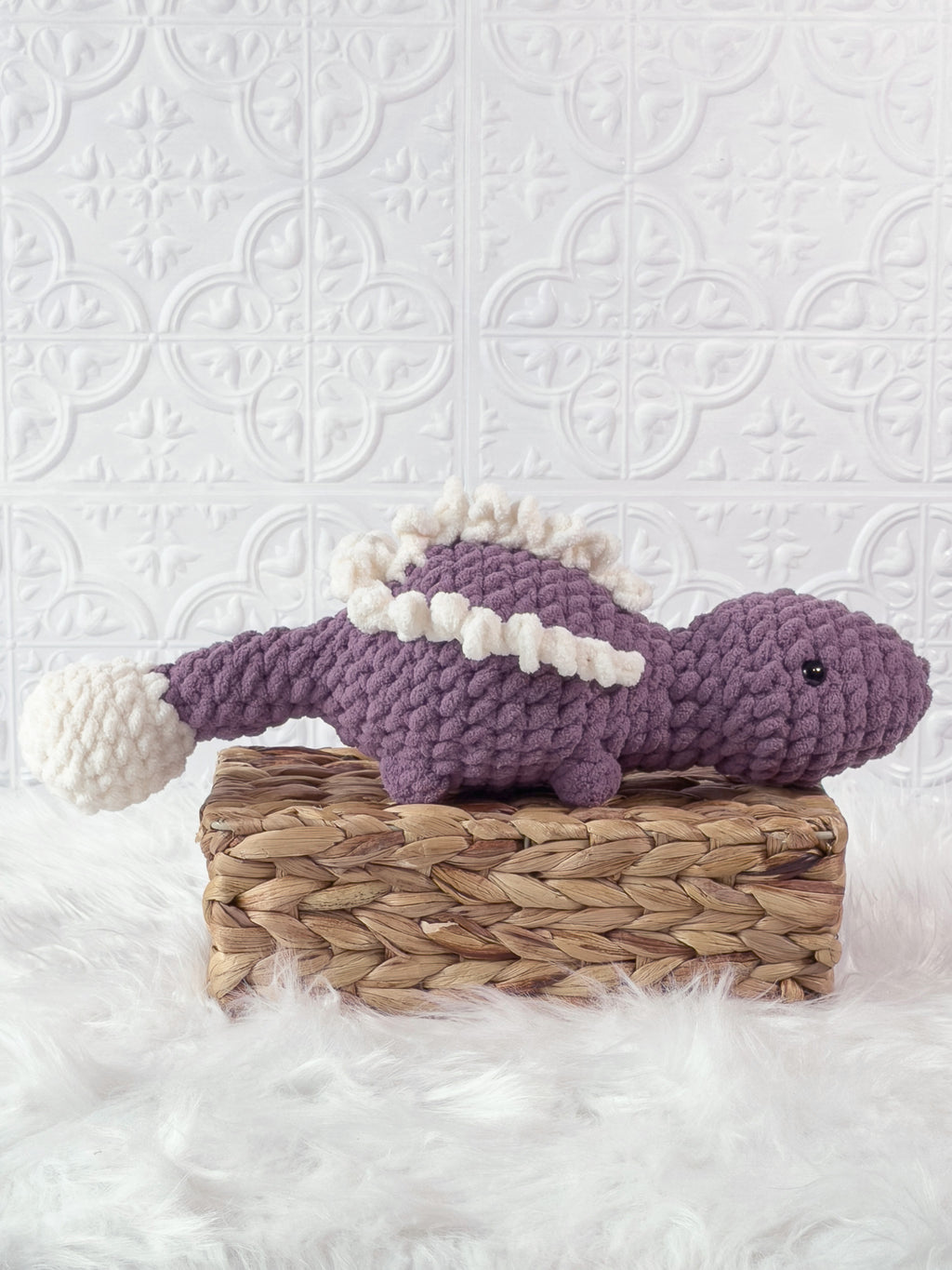 Handmade purple stegosaurus crochet plushie shown from the side
