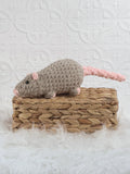 Taupe and pink handmade rat crochet plushie with a long tail displayed on a woven basket