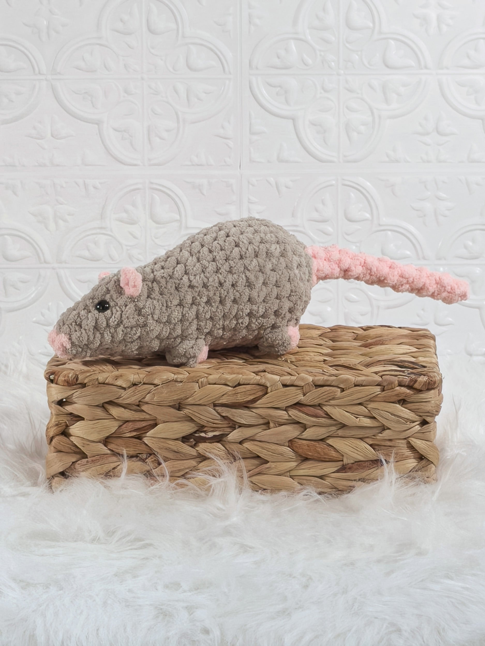 Taupe and pink handmade rat crochet plushie with a long tail displayed on a woven basket