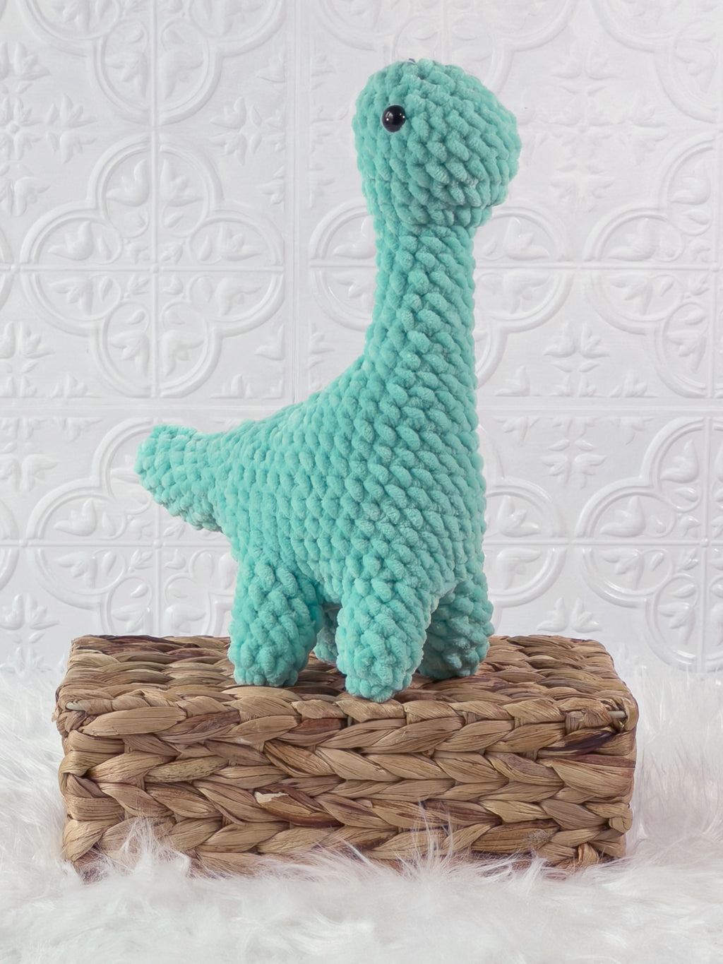 Handmade turquoise brachiosaurus crochet plushie shown from an angled view