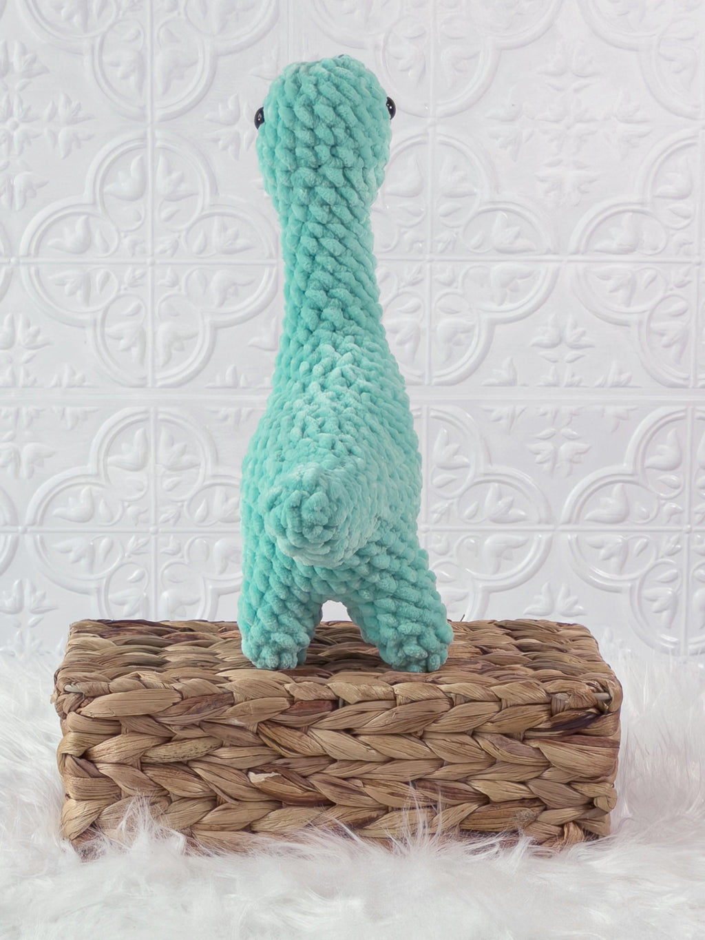 Handmade turquoise brachiosaurus crochet plushie shown from the back