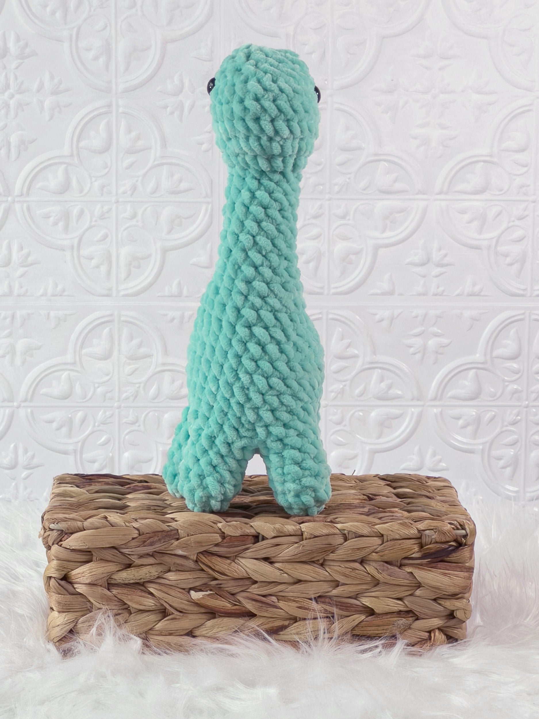 Handmade turquoise brachiosaurus crochet plushie shown from the front
