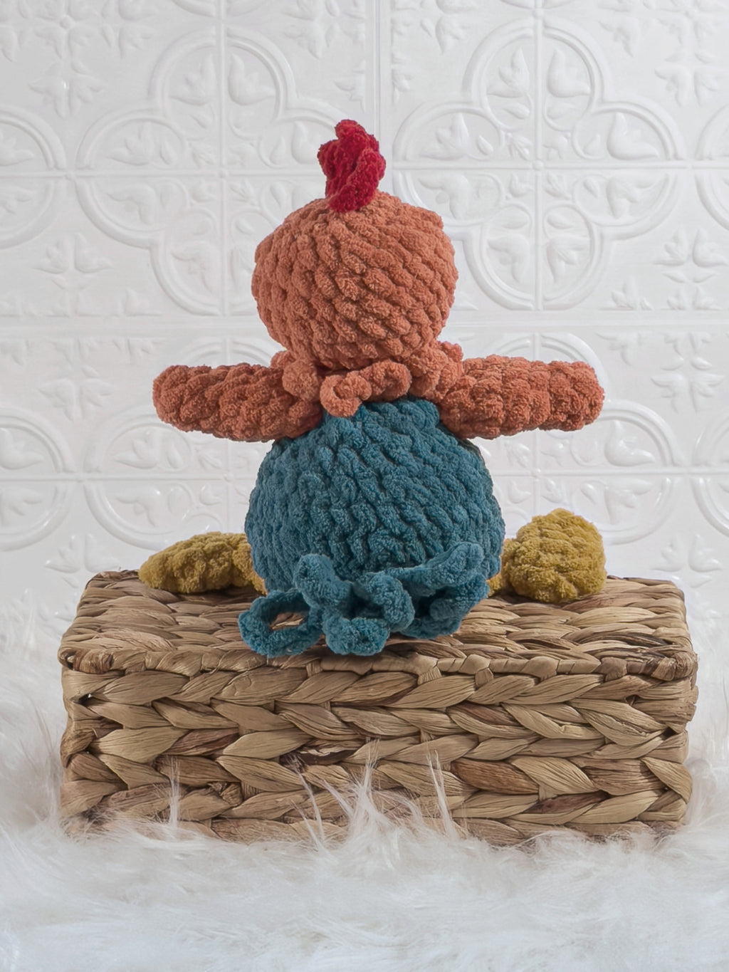 Handmade turquoise sitting rooster crochet plushie shown from the back