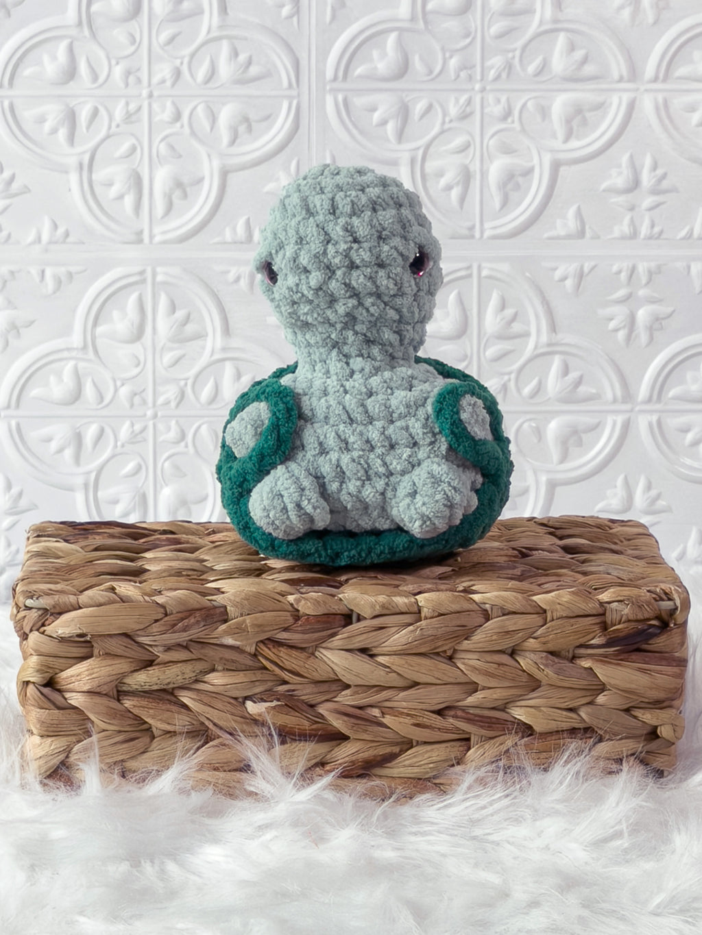 Handmade turquoise, dark turtle crochet plushie shown from an angled view