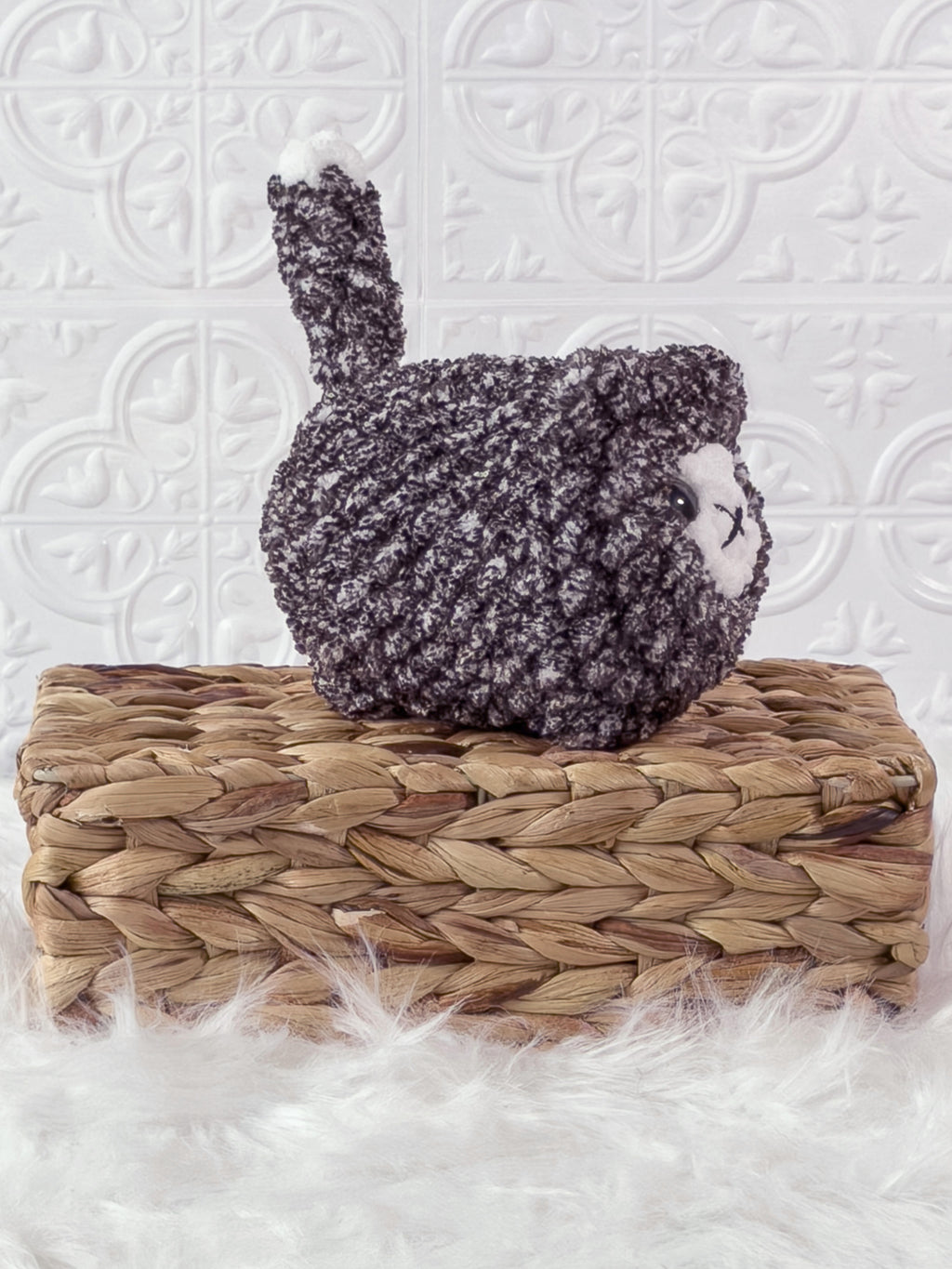 Handmade tweed, black loaf cat crochet plushie shown from an angled view